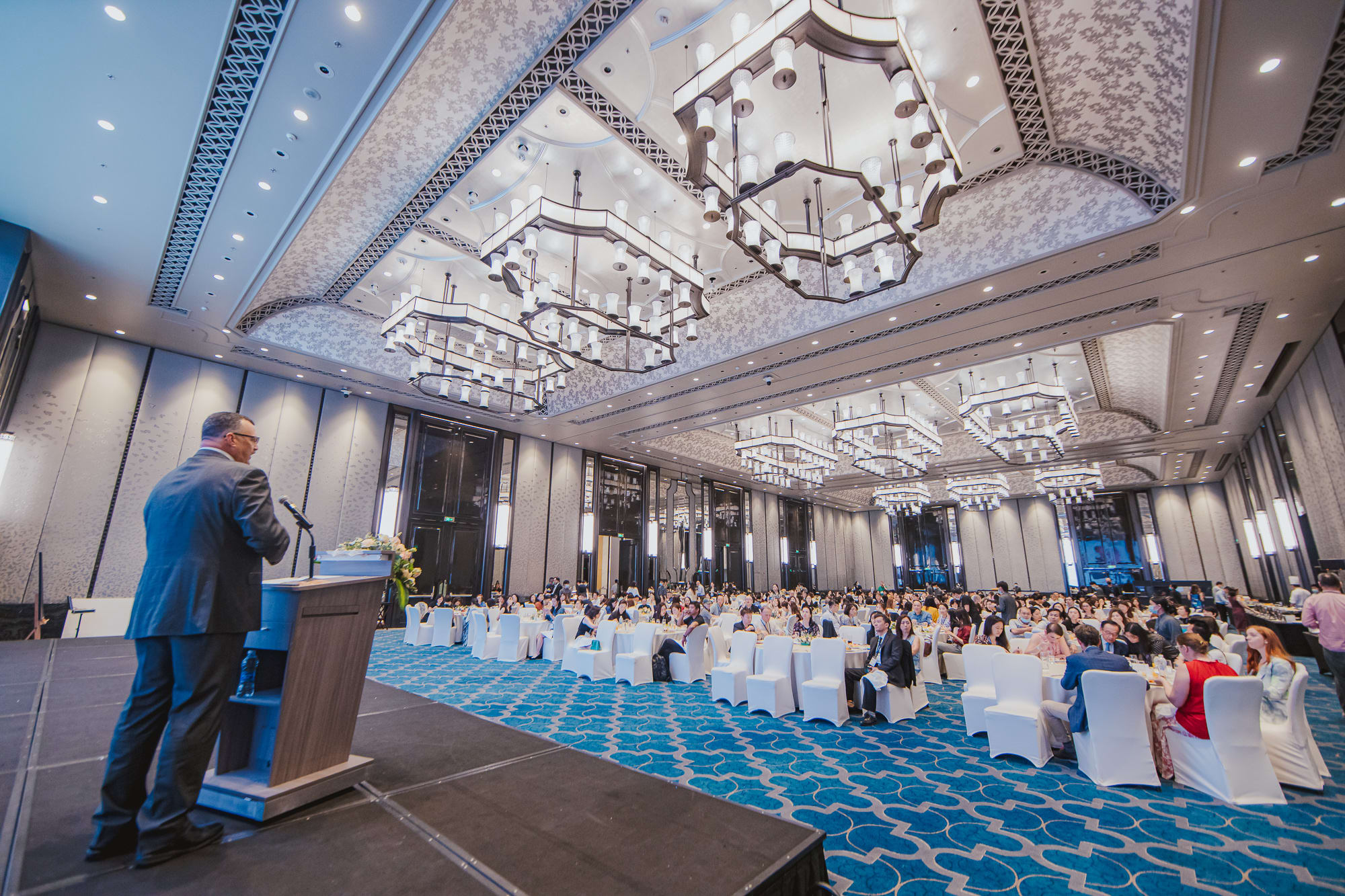 man on stage talking to big audience sitting