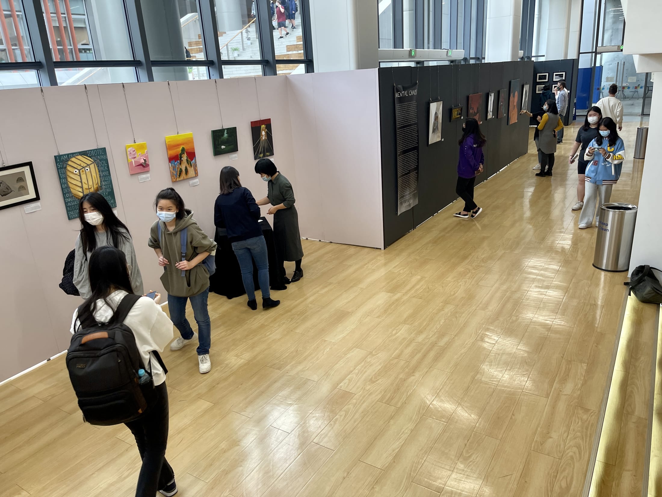 AISG IB Visual Art Exhibition with students and teachers walking through the hallway and looking at the art