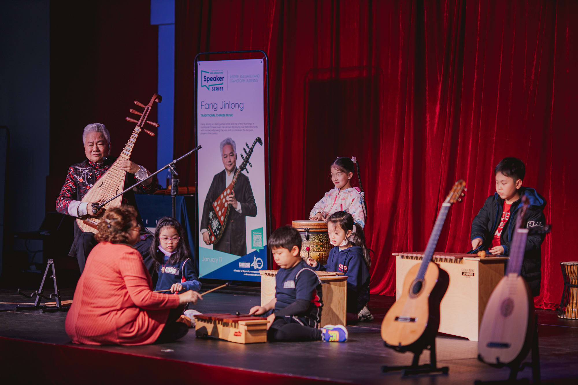 AISG Speaker Series with Fang Jinlong playing his pipa with elementary students on stage