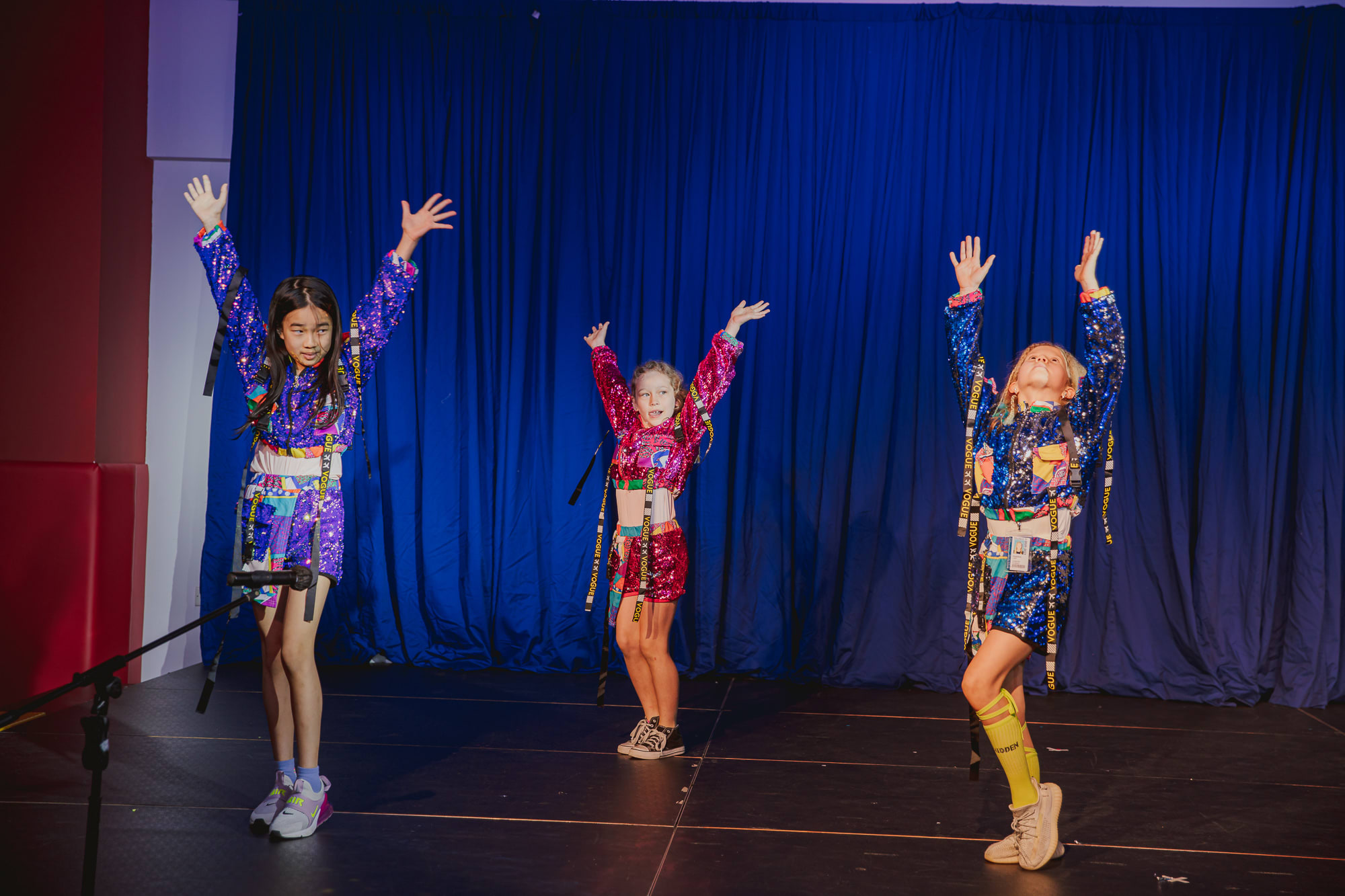 three girls in colorful costumes dancing on stage