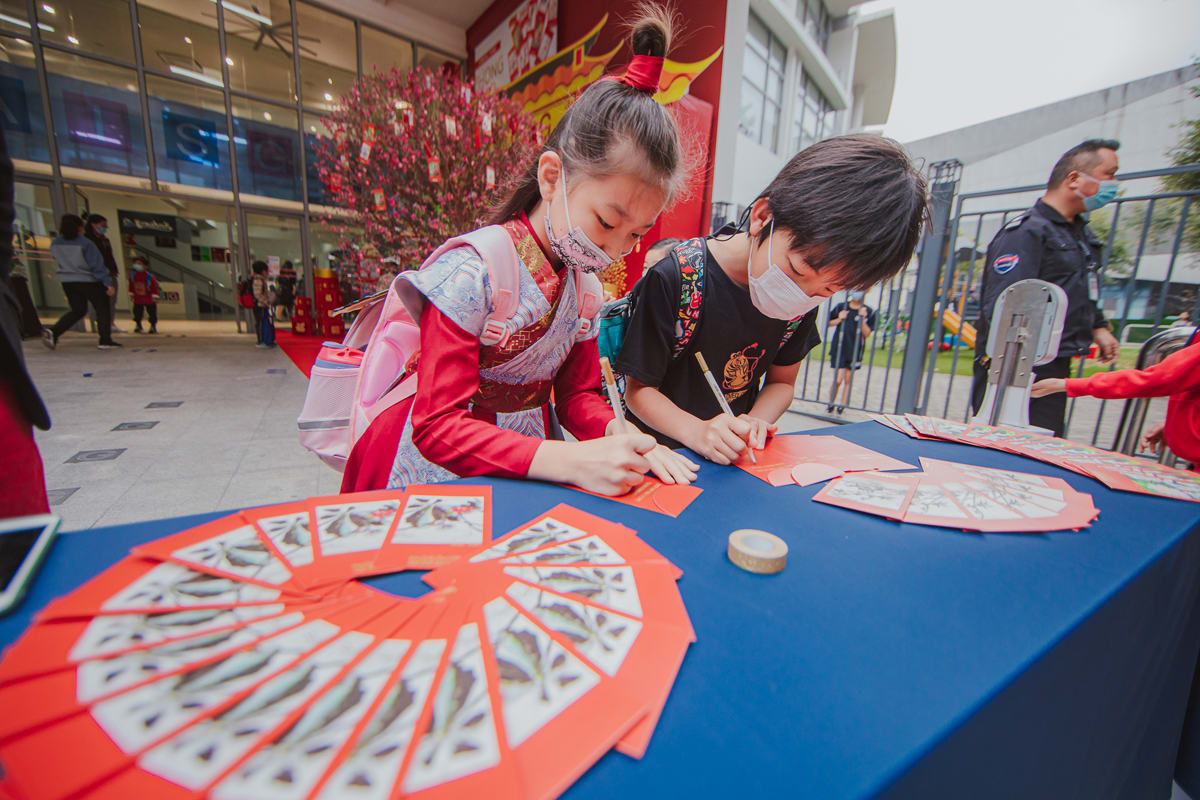 students creating envelopes for giving at the Hong Bao celebration