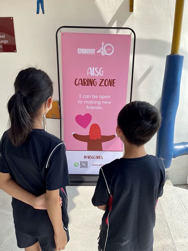 Elementary students reading the caring pledge for AISG Cares