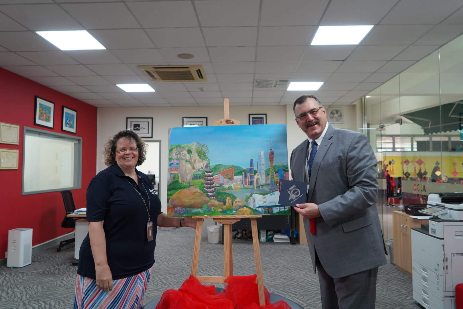 At AISG's 40th birthday celebration, a teacher gives AISG a painting gift