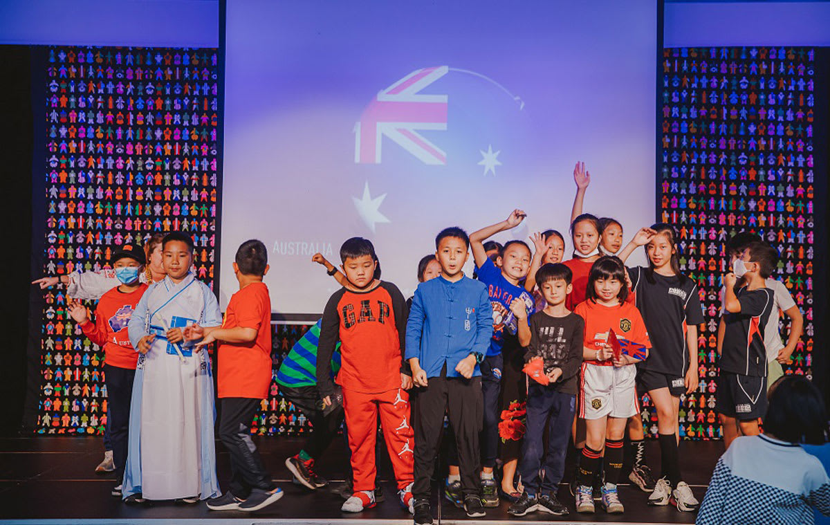 students standing on a stage at UN day with the Australian national flag flying behind them
