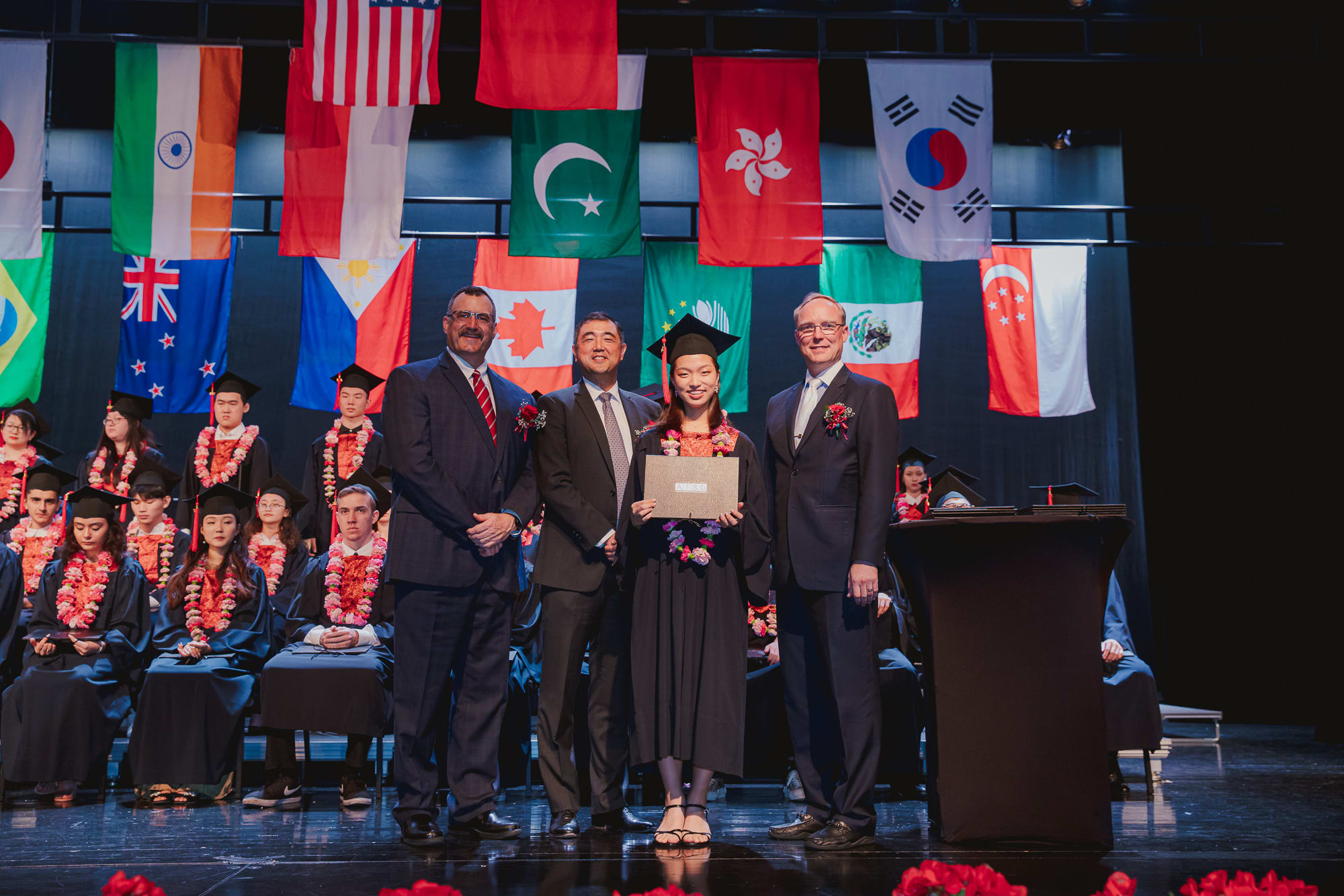 student smiling with diploma with principal director board of governors