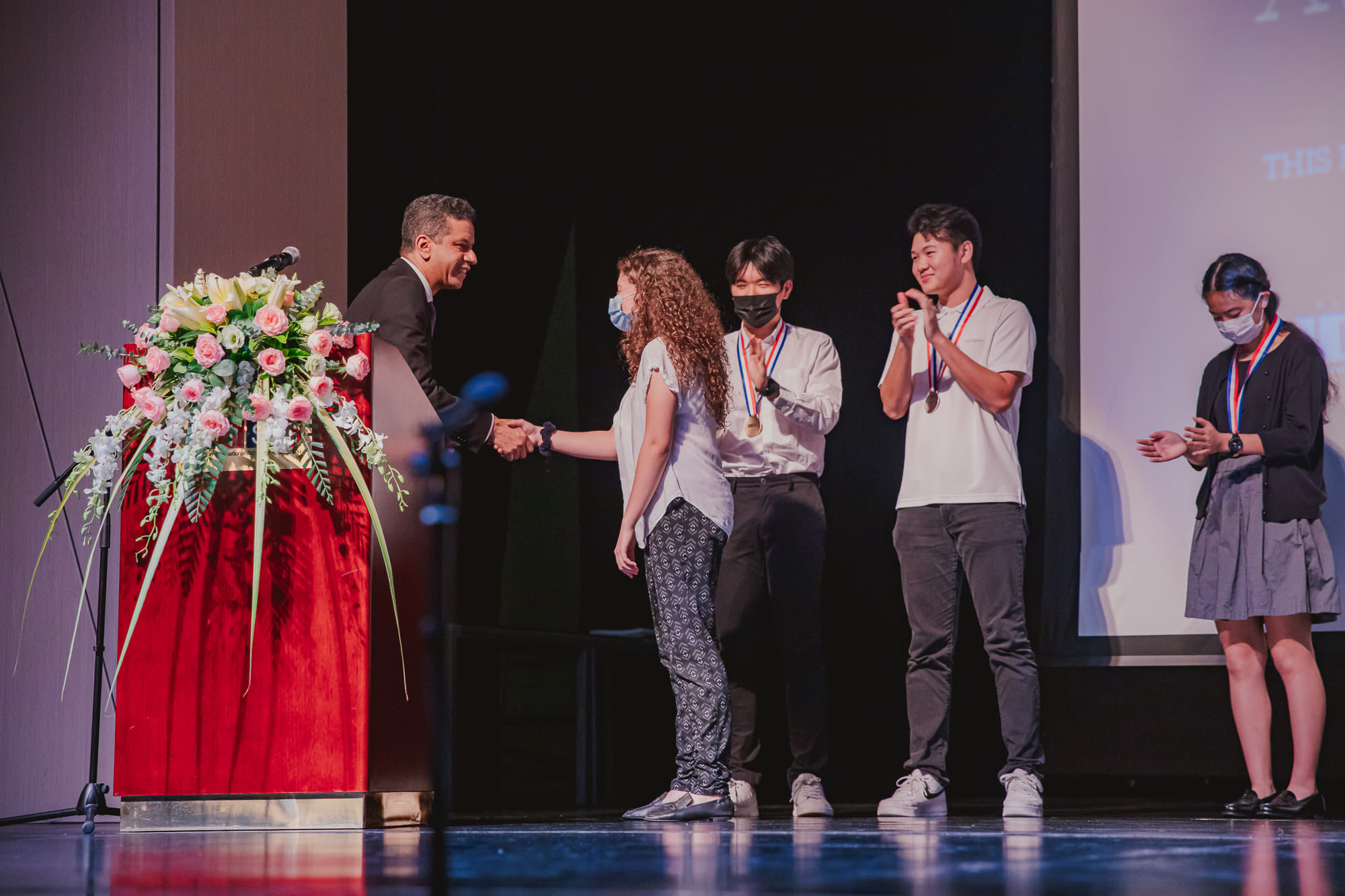 AISG Athletics & Activities Awards Ceremony with student shaking hands with tennis coach