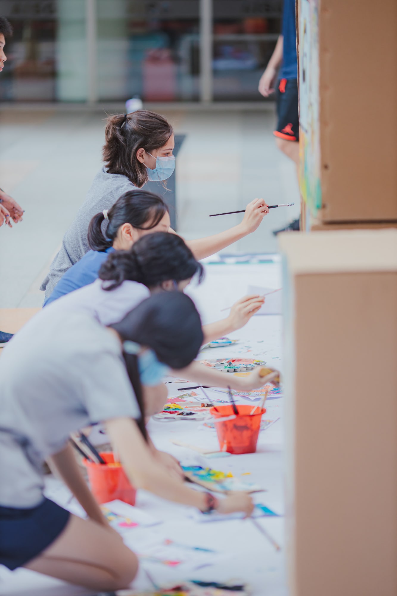 row of students painting while kneeling
