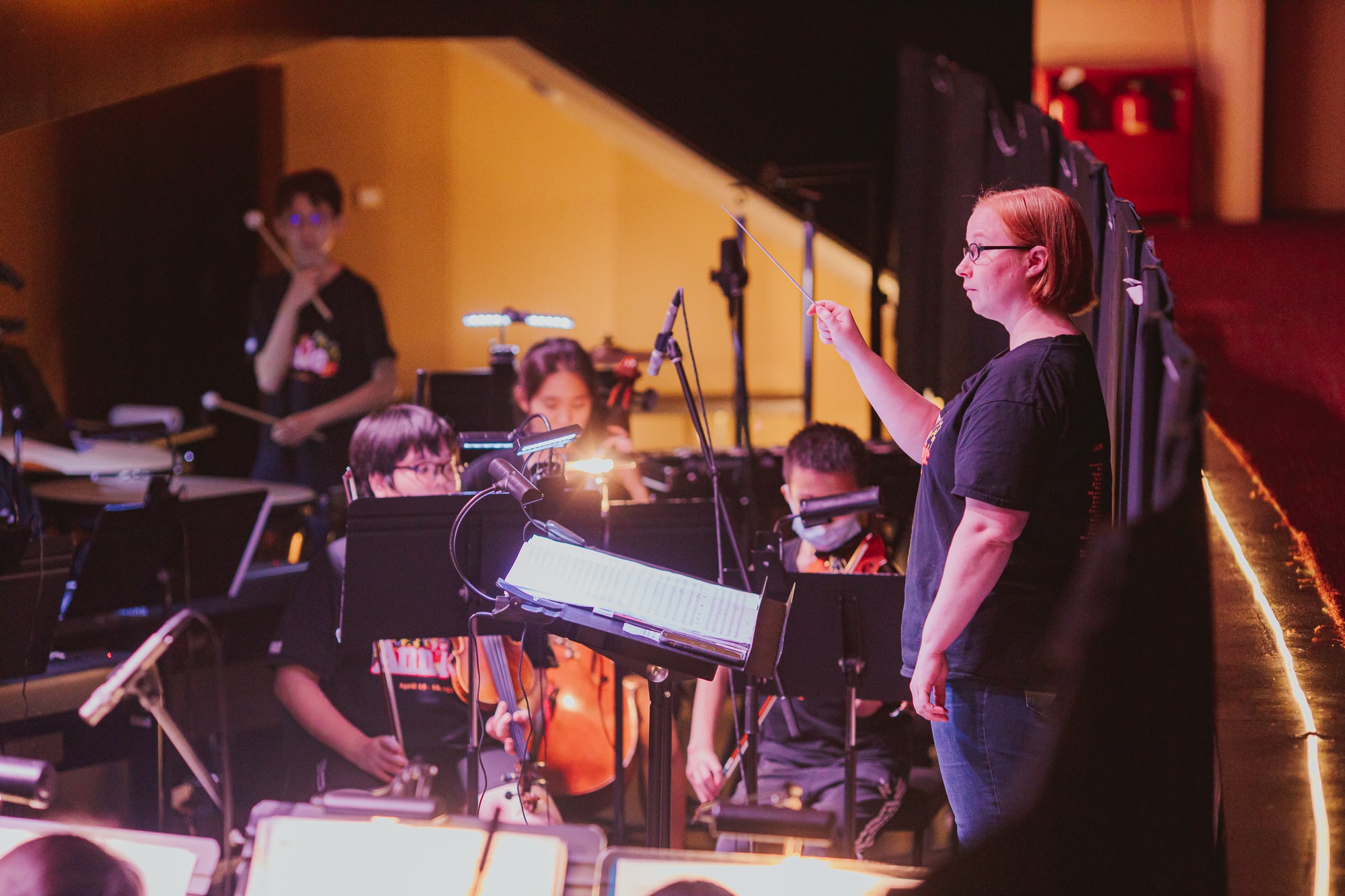 teacher conducting students in the orchestra pit