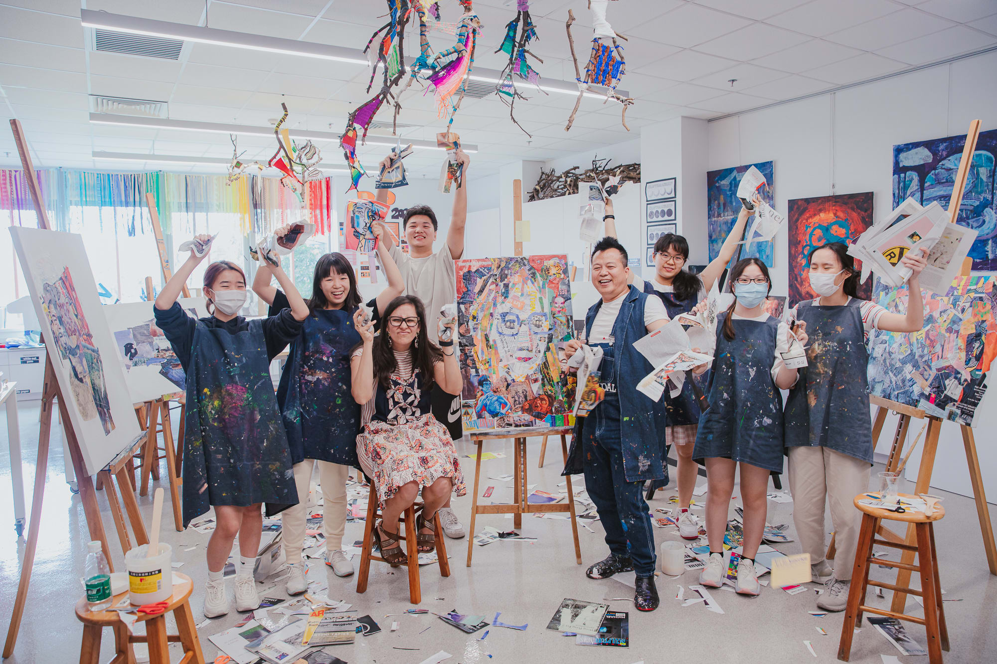 students artist and teacher pose for group photo with collage supplies