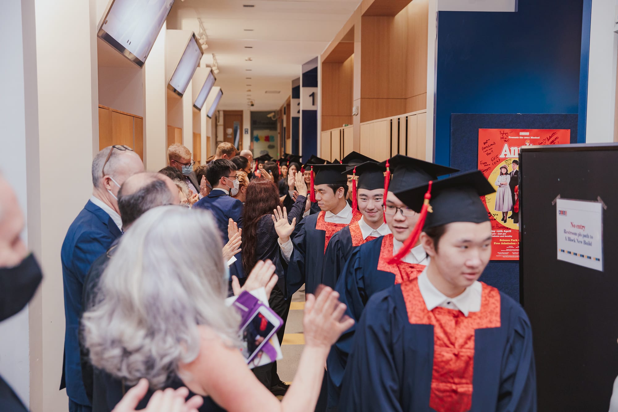 graduates walking down a hall highfiving teachers