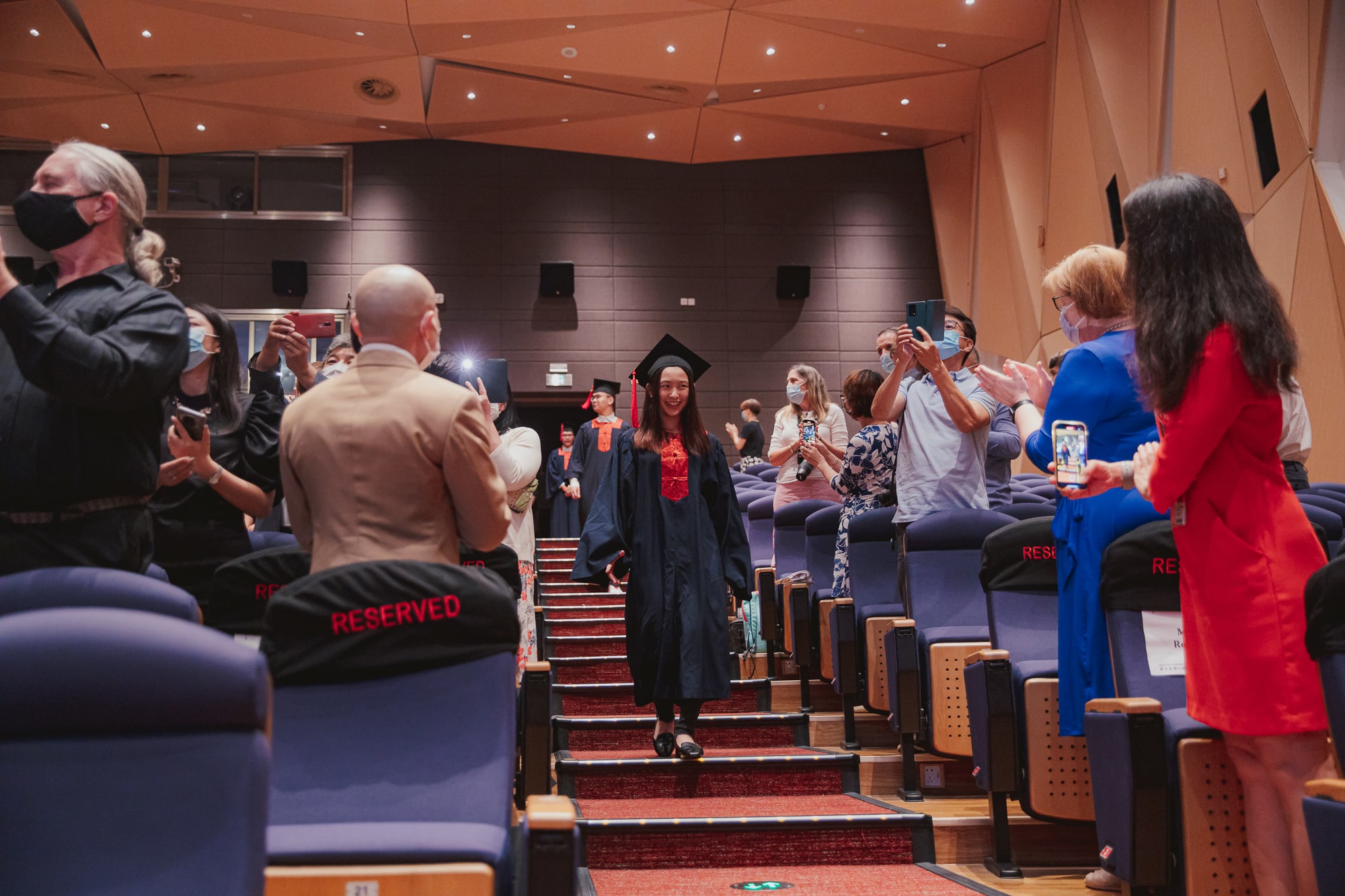 graduates walking down stairs in theaters getting applause
