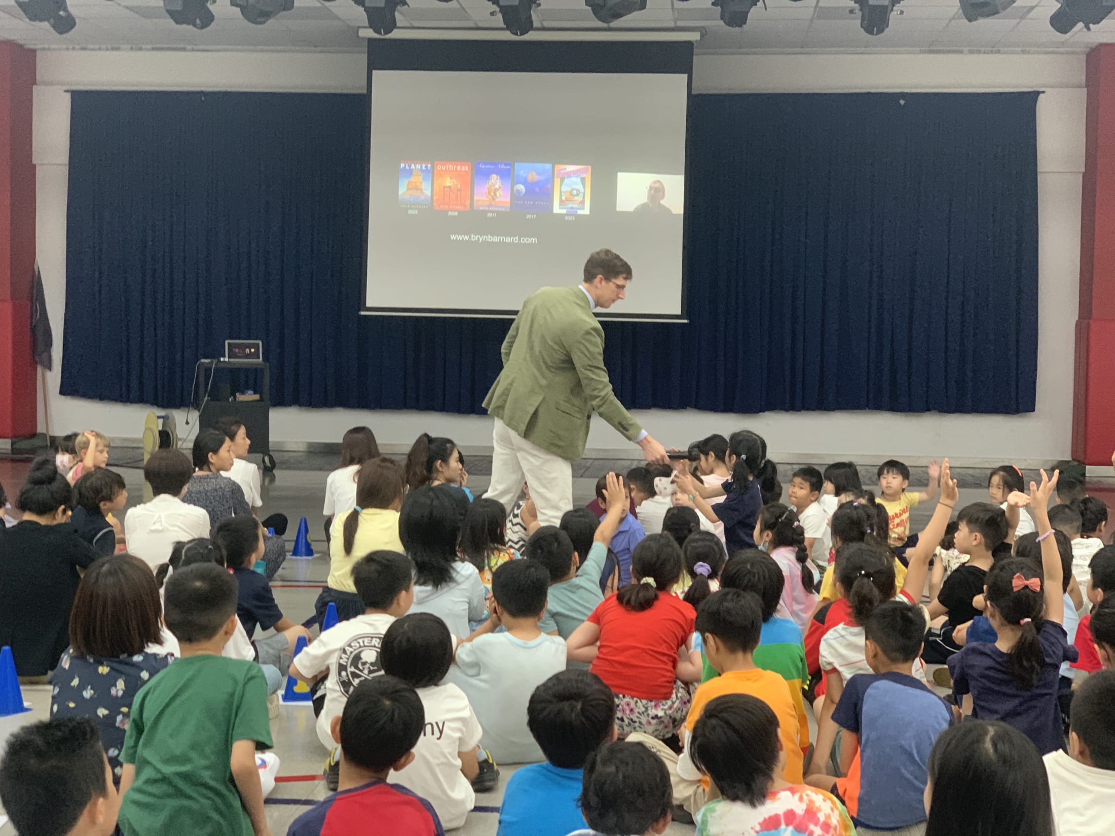 man handing child a microphone to ask question in a crowd of children