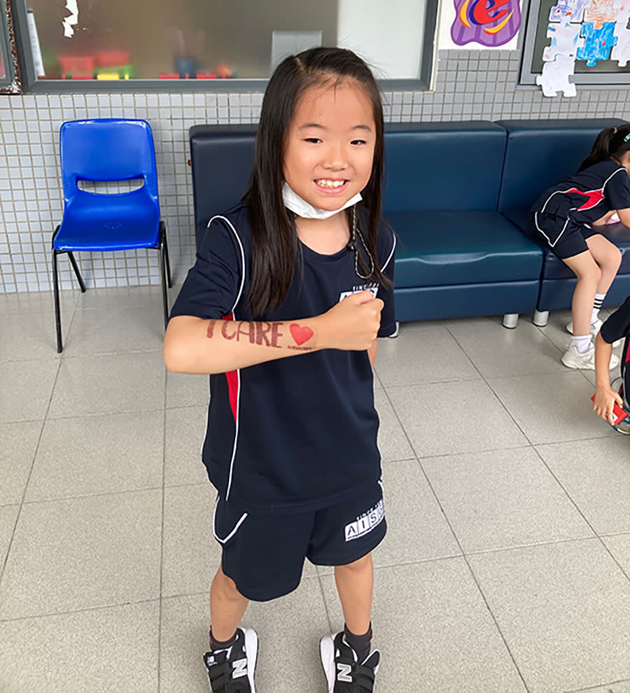 AISG Cares event with an elementary student showing off her I Care tattoo