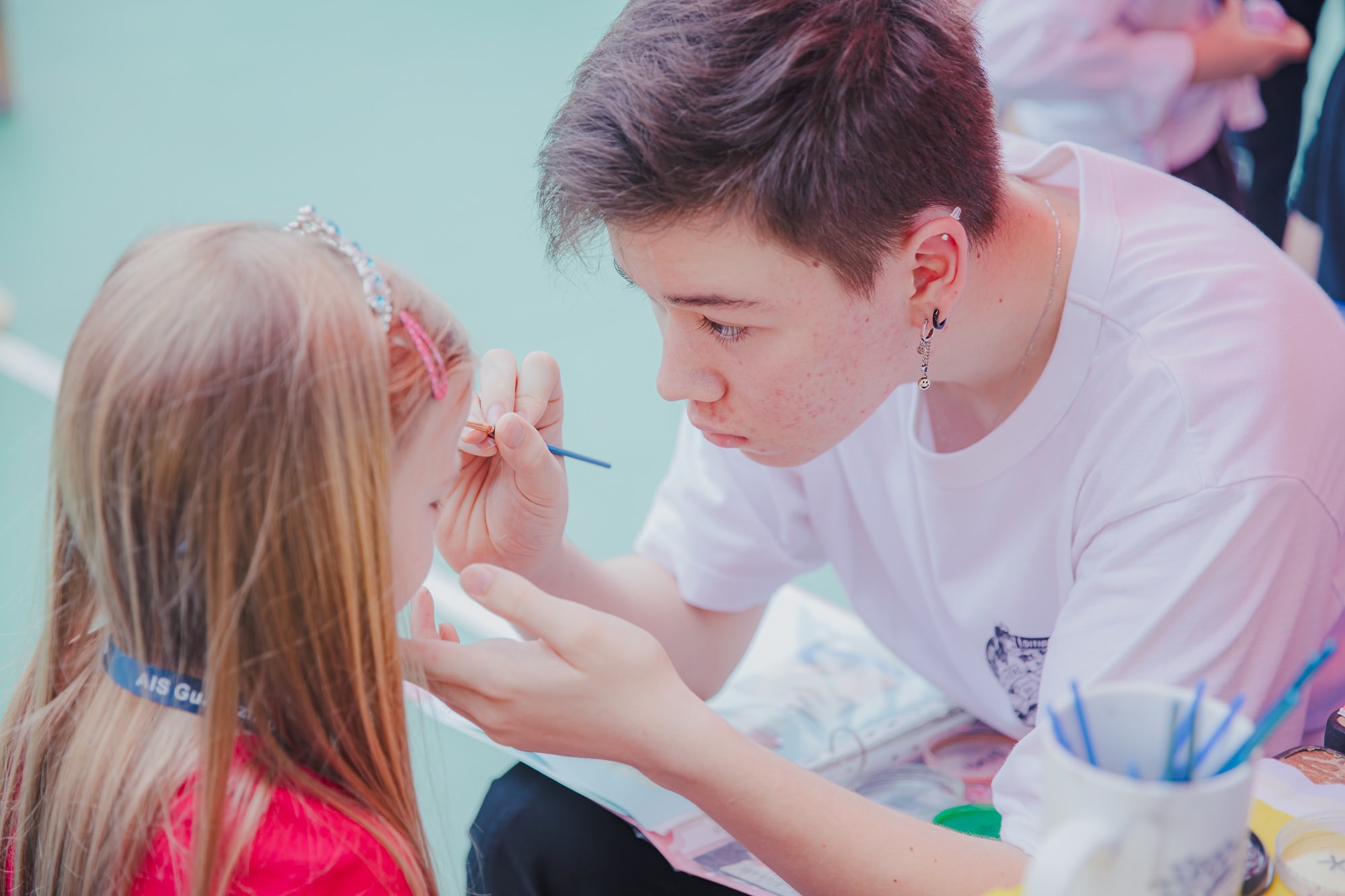 teenage boy painting the face of a child