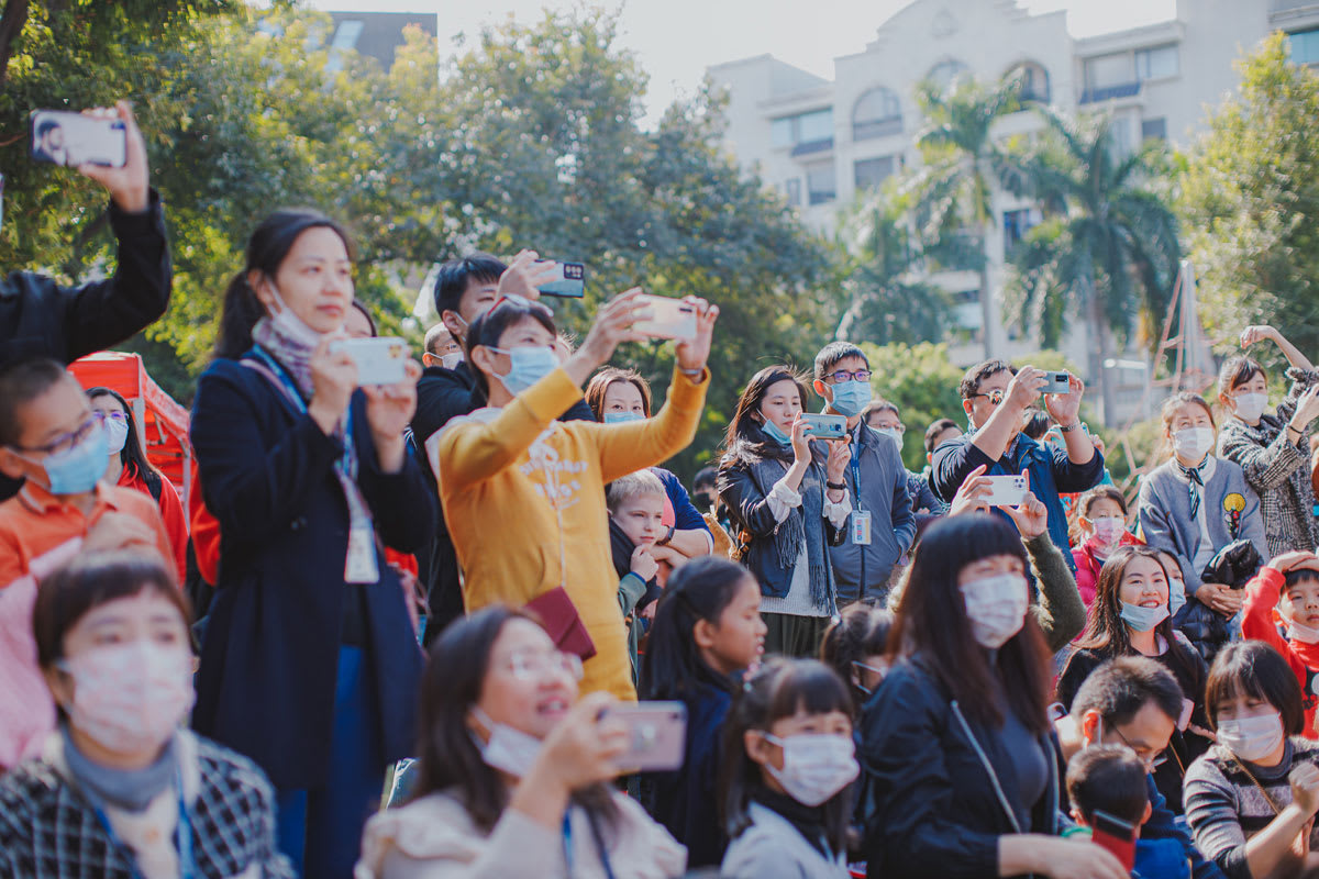 a crowd of parents watching their children perform are taking pictures with their cell phones