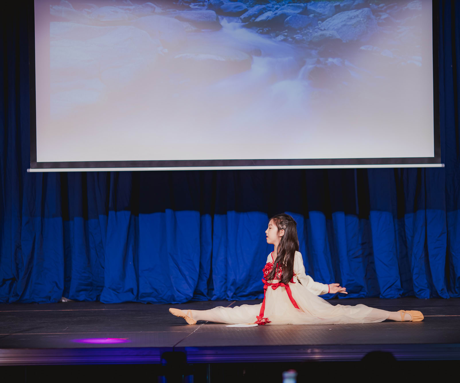 girl in white dress doing the splits onstage