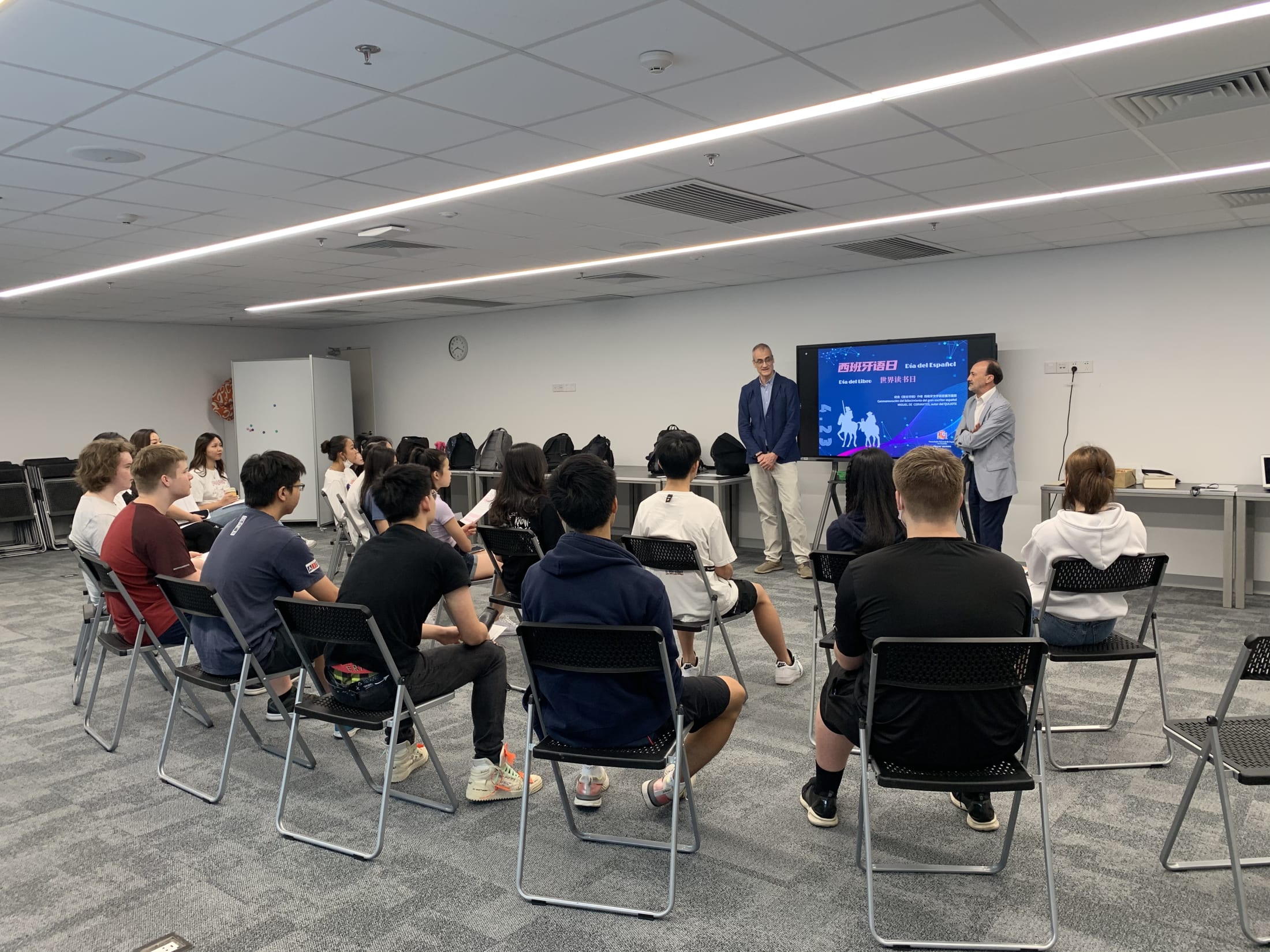 students looking at two adults in front of a tv screen 