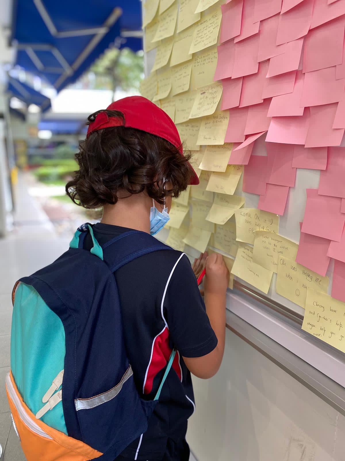 a student adds a sticky note to the Caught You Caring whiteboard