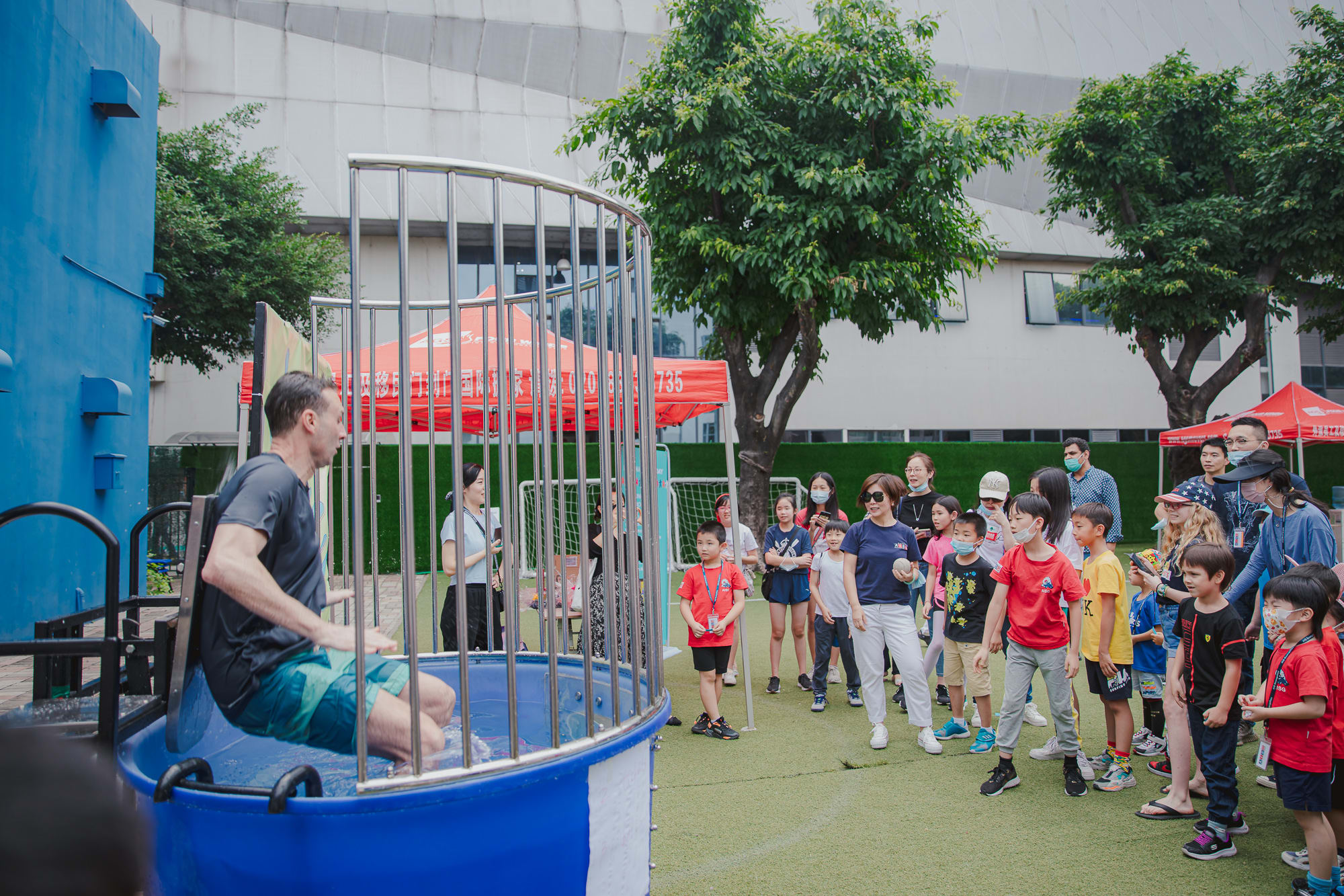 man falling into dunk tank as crowds of children watch