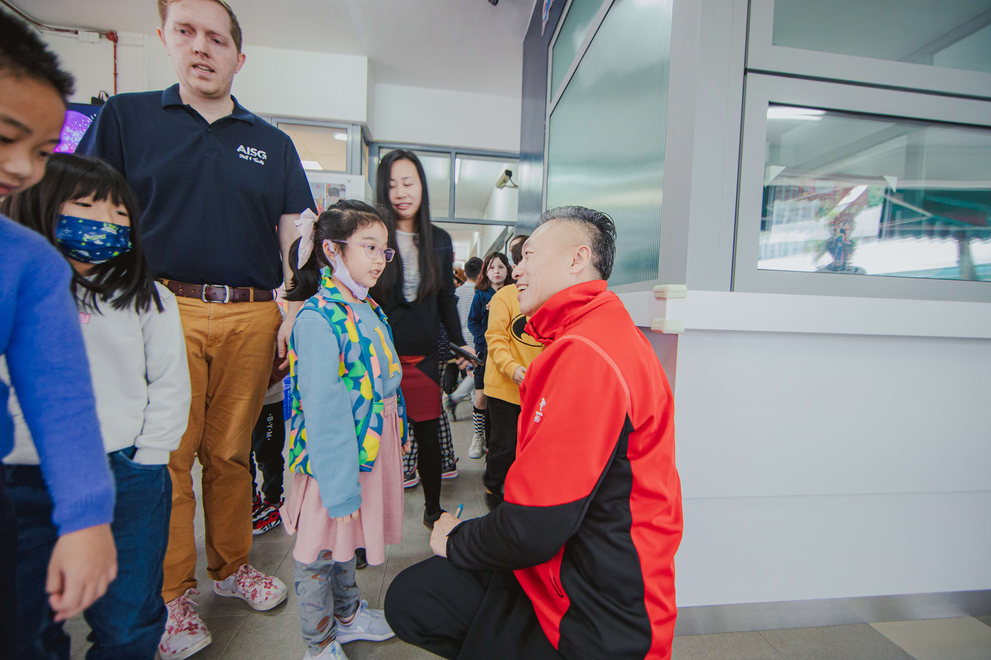 AISG Speaker Series with Hou Bin kneeling down to talk to an elementary student