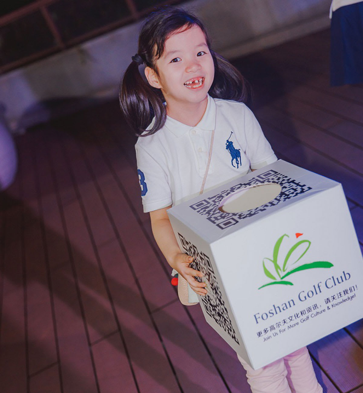 a young girl holds a box full of tickets for a drawing