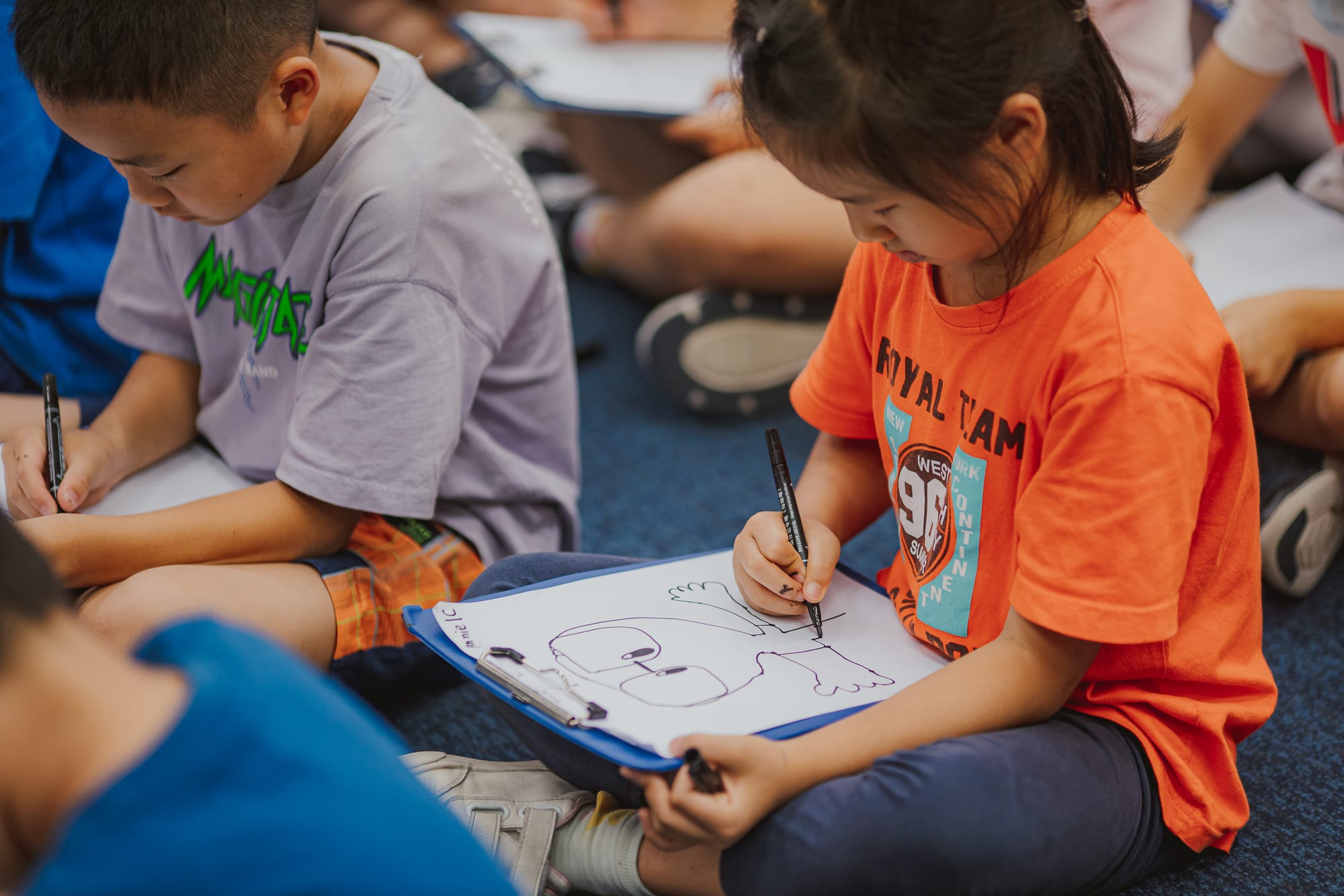 students sitting on the floor drawing