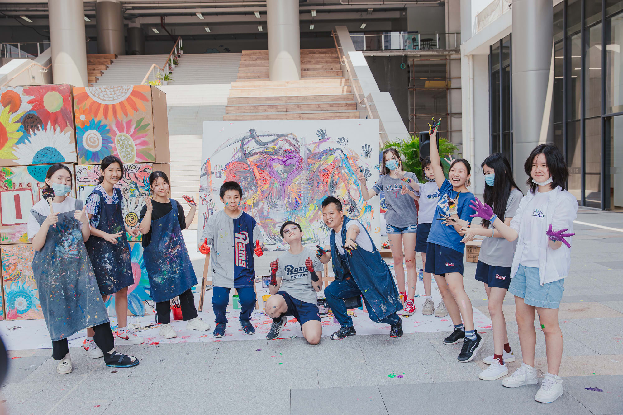 students pose with finished abstract canvas