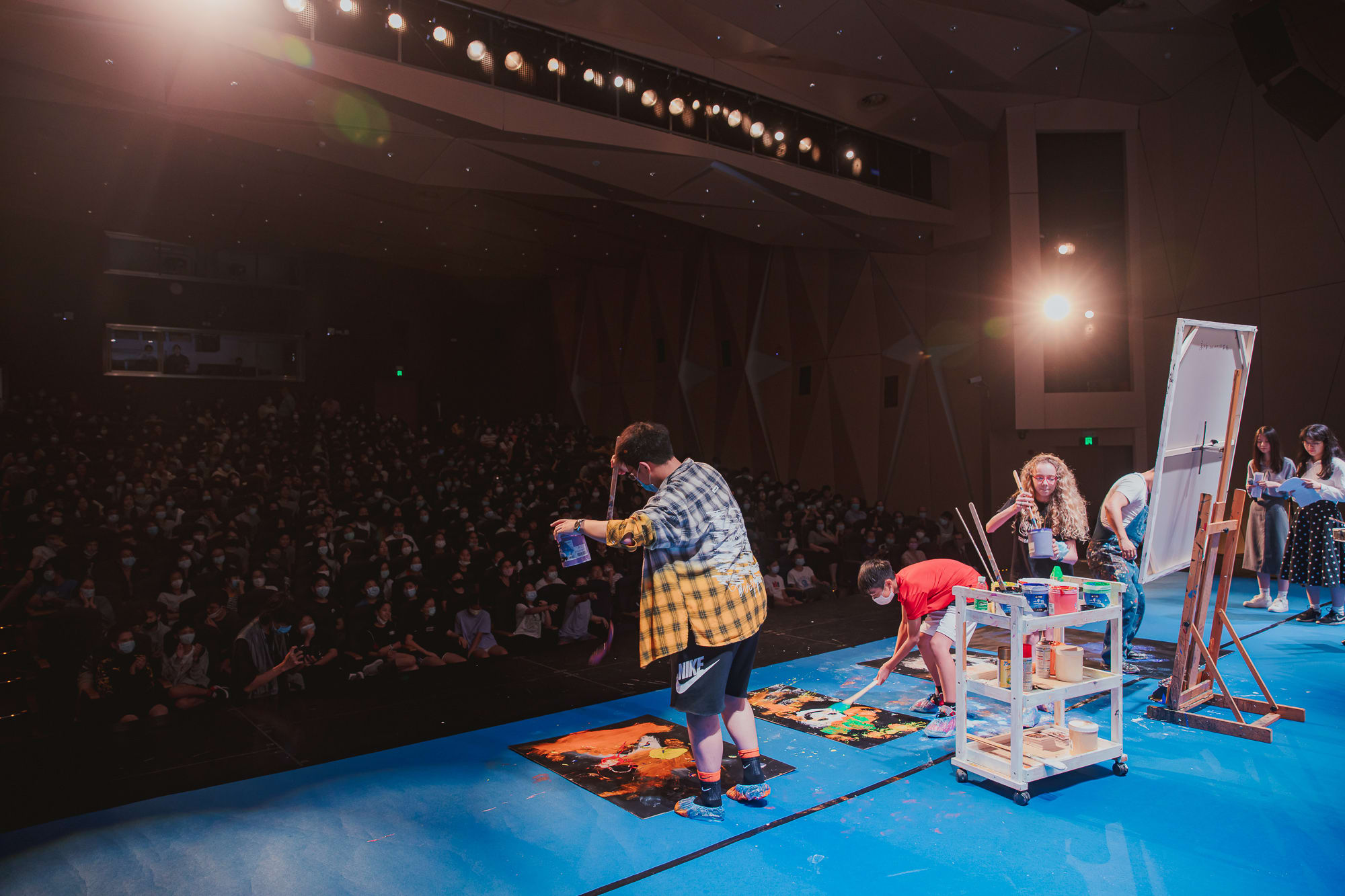 students onstage with artist doing painting by stepping on boards