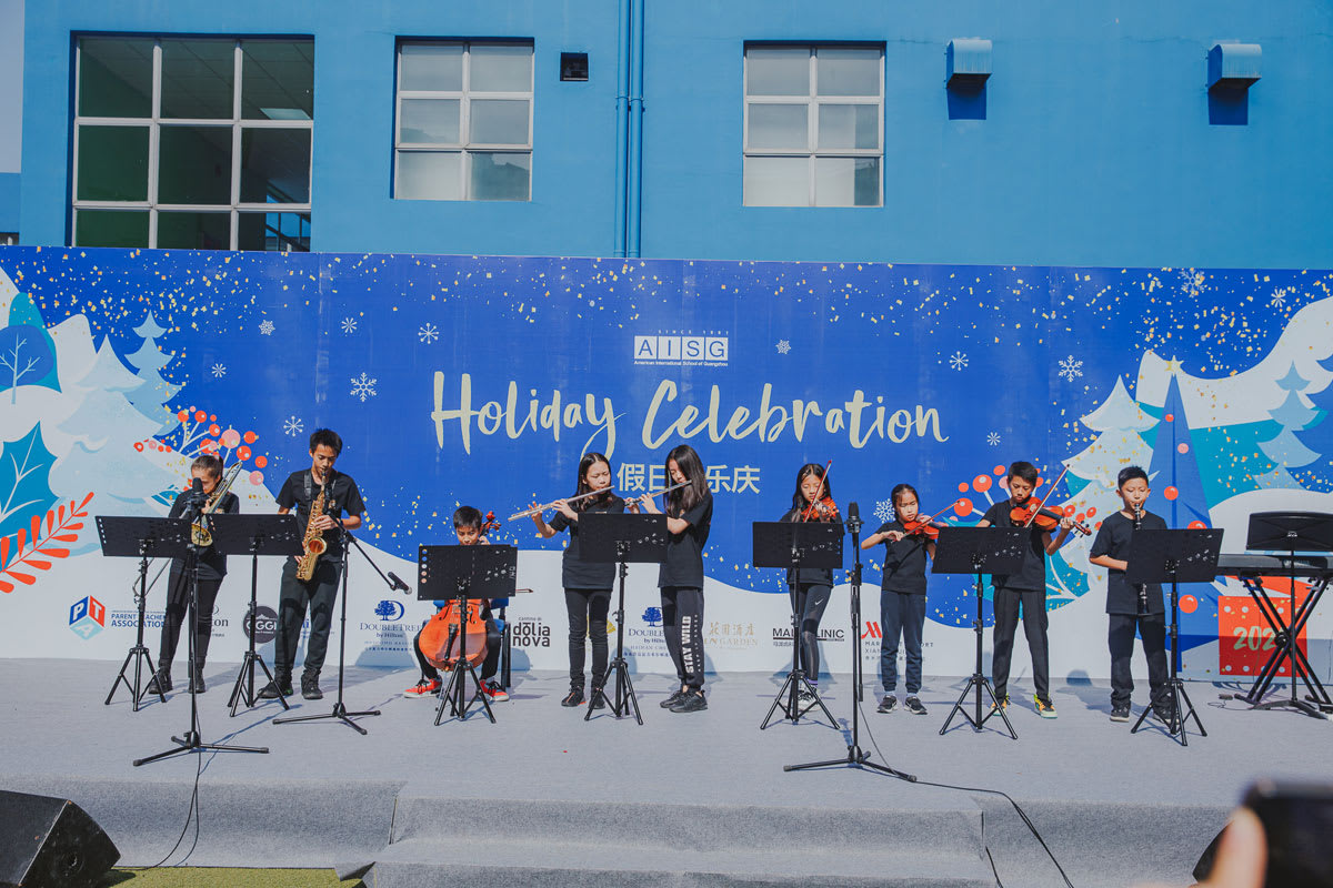 students playing in an orchestra on stage at the holiday celebration