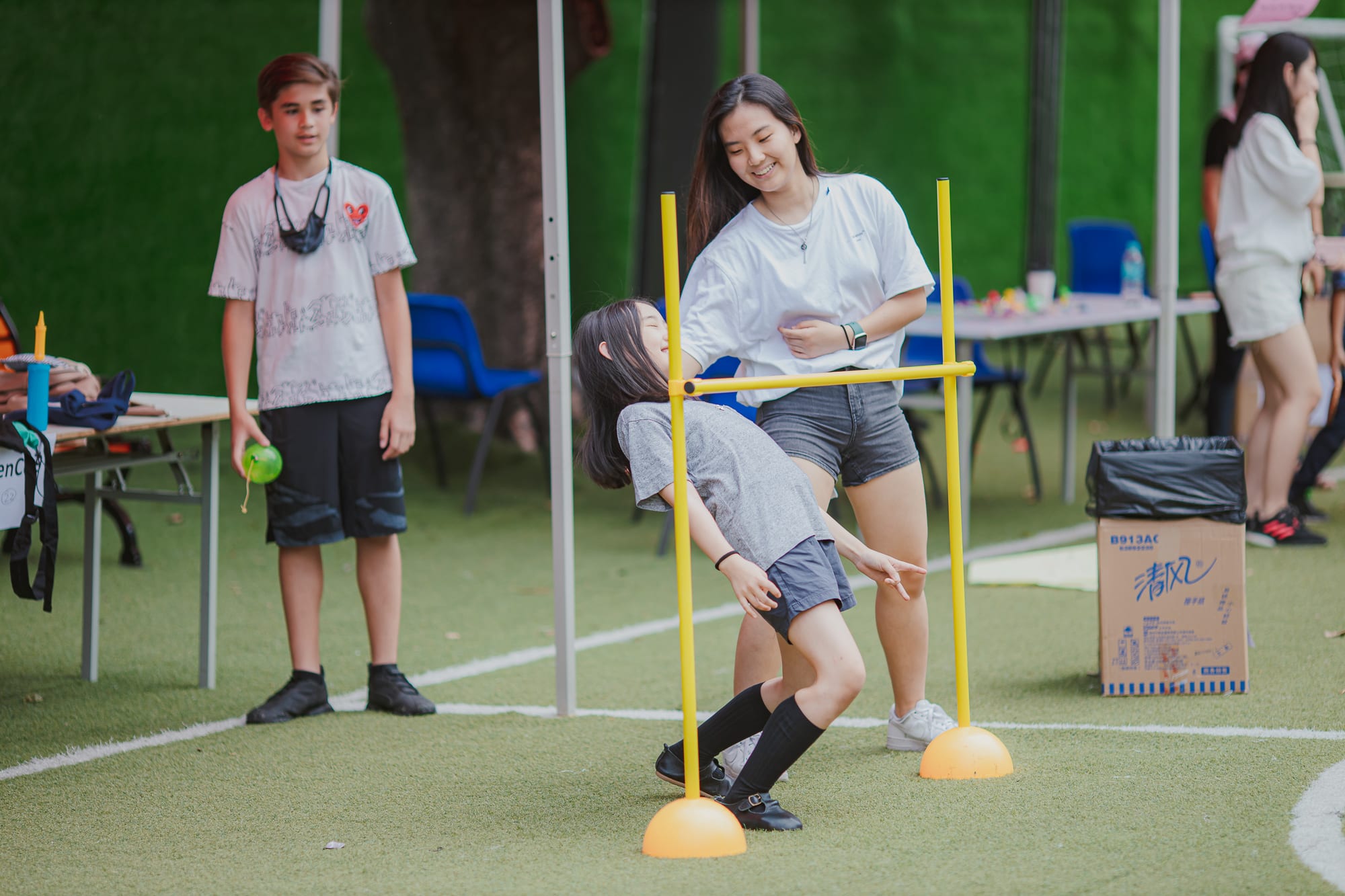 young girl bending down doing limbo while older girl watches