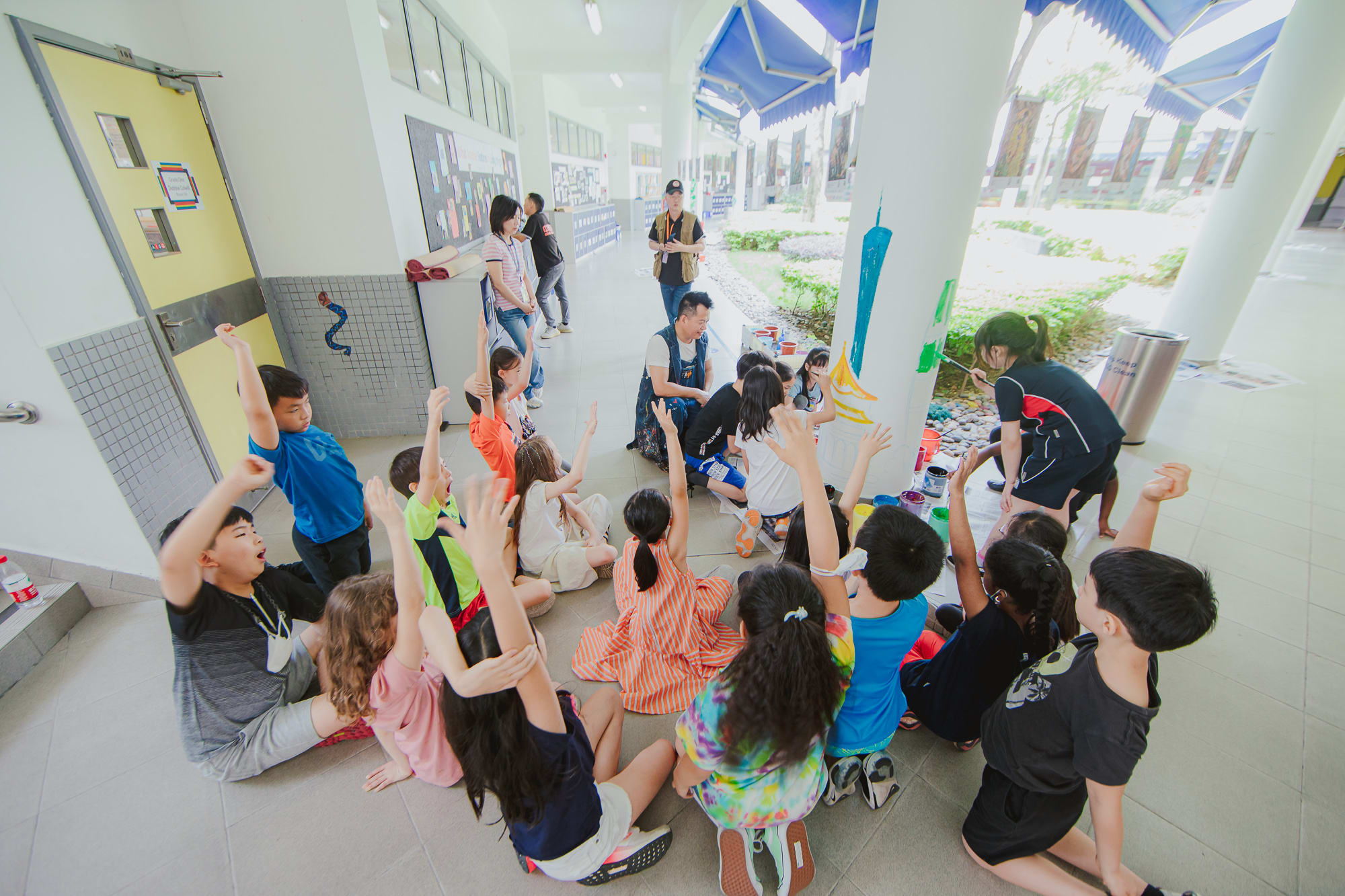 students raise their hands to paint next