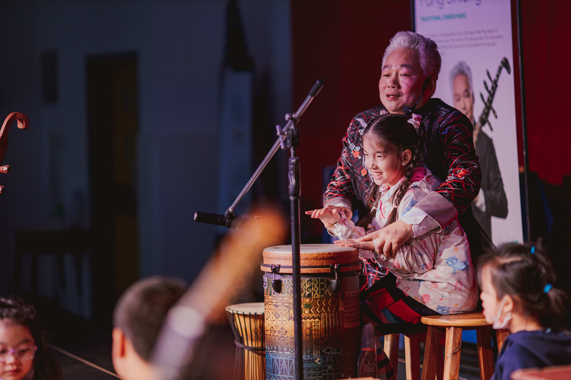 AISG Speaker Series with Fang Jinlong plays the drums with an elementary school student