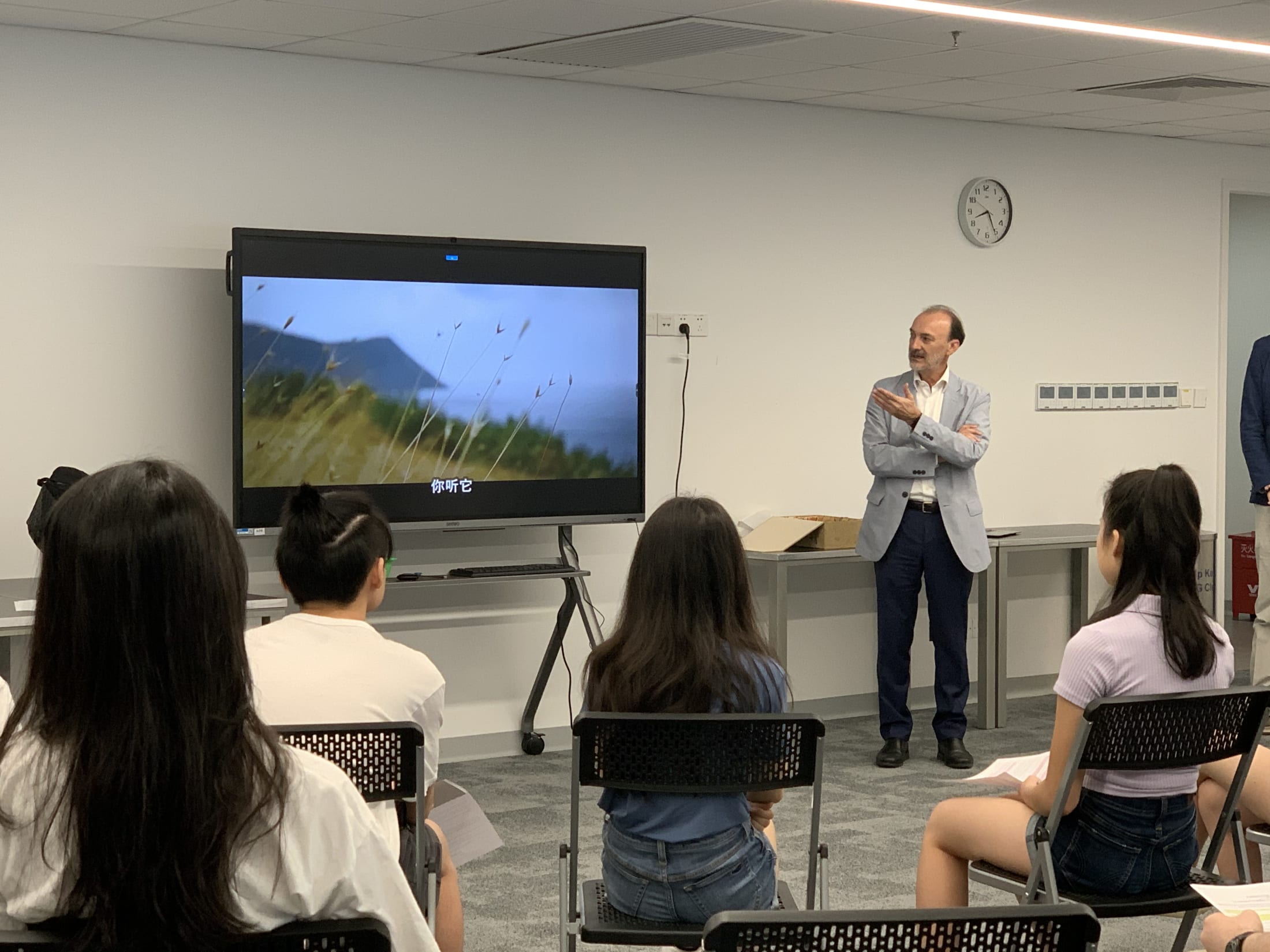 man presenting a video on a screen to students