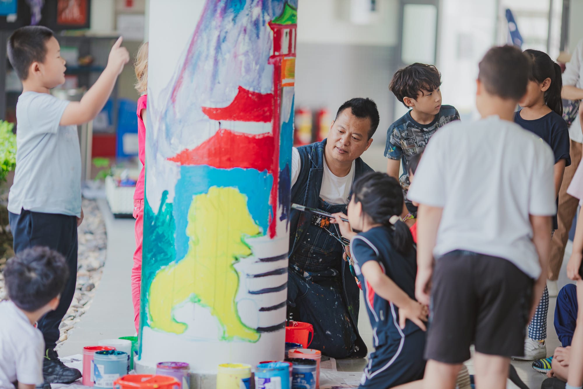 students painting temple scene on a pillar