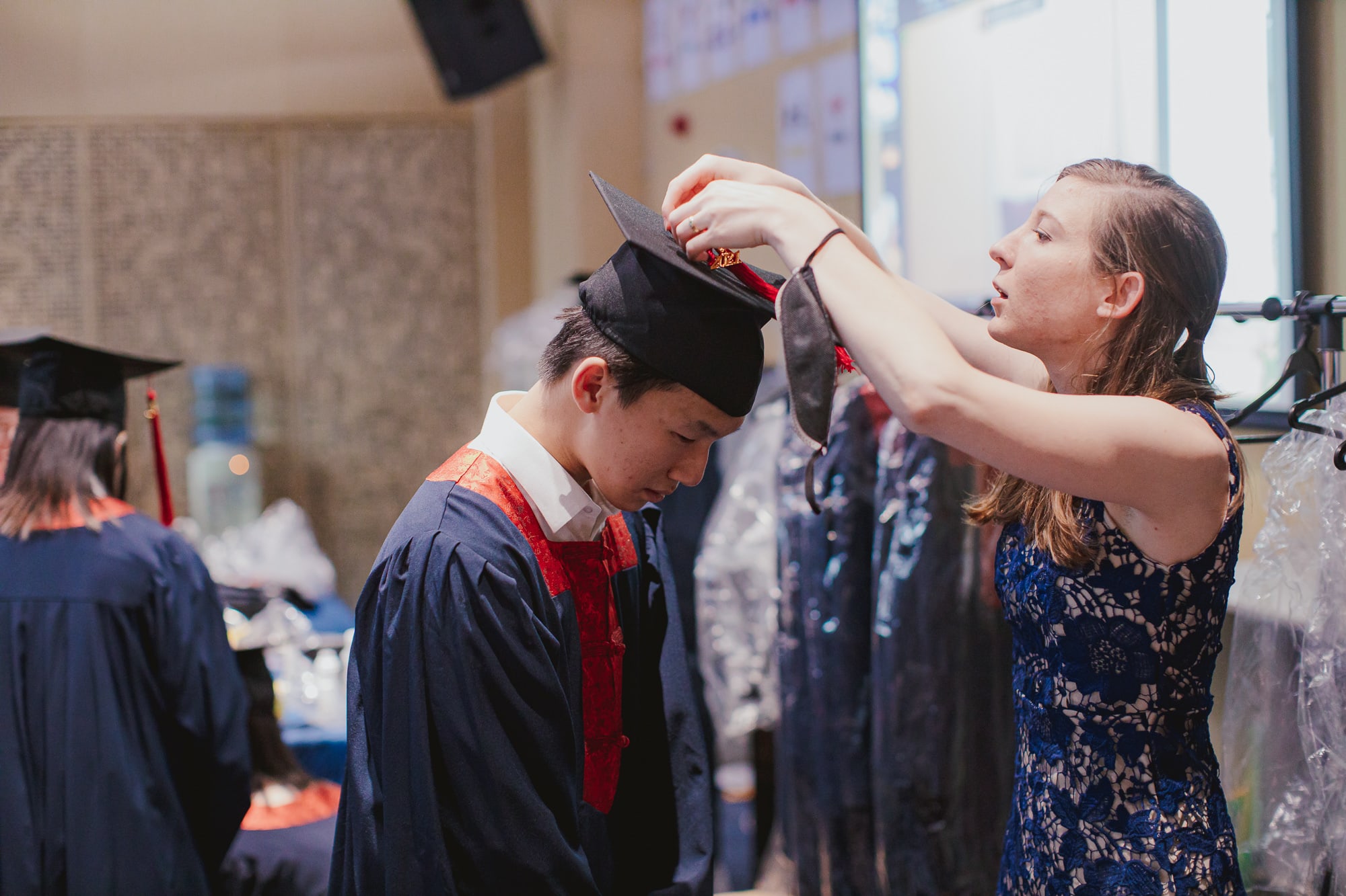 teacher fixing student's graduation cap