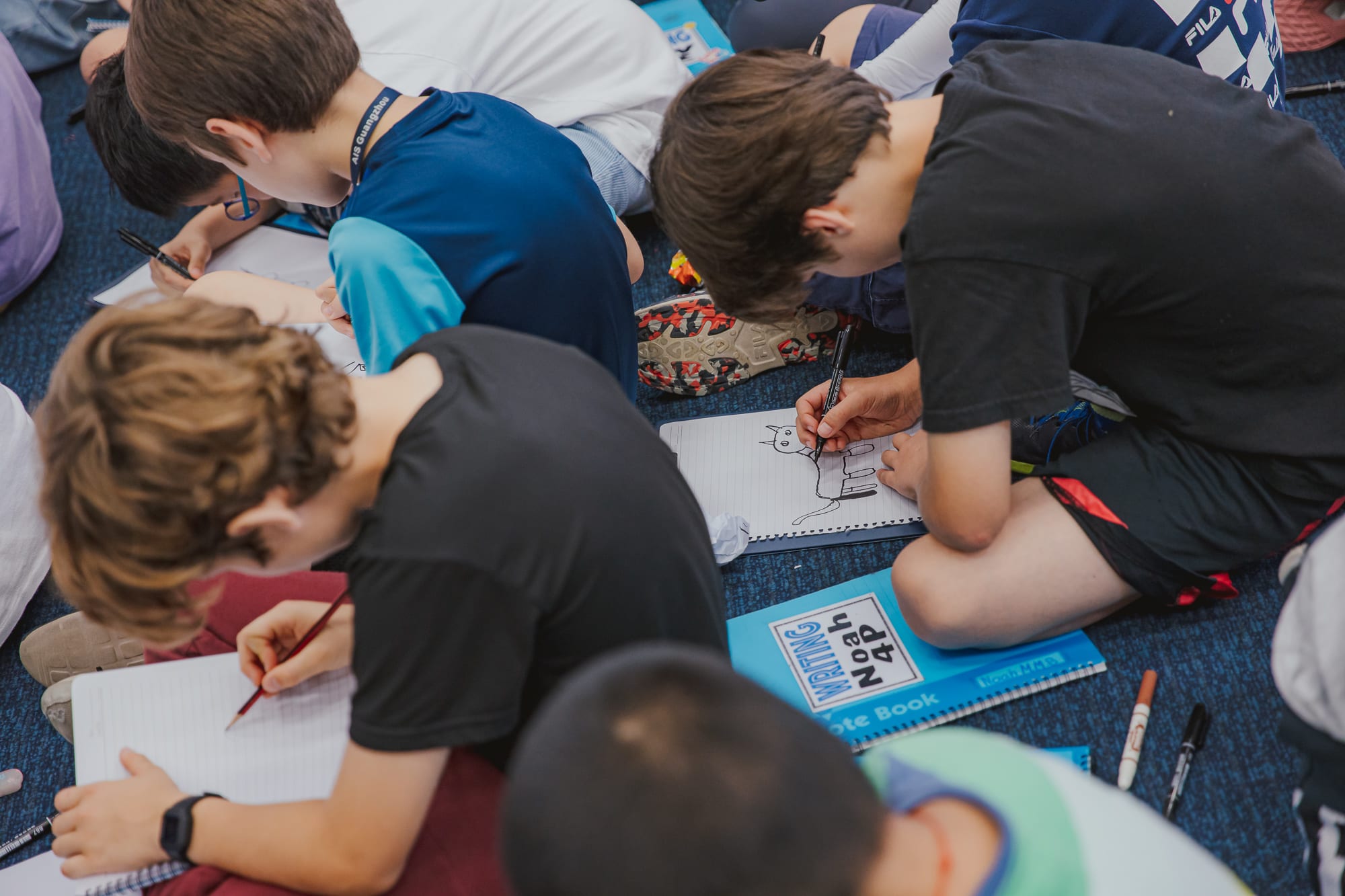 students sitting on floor drawing