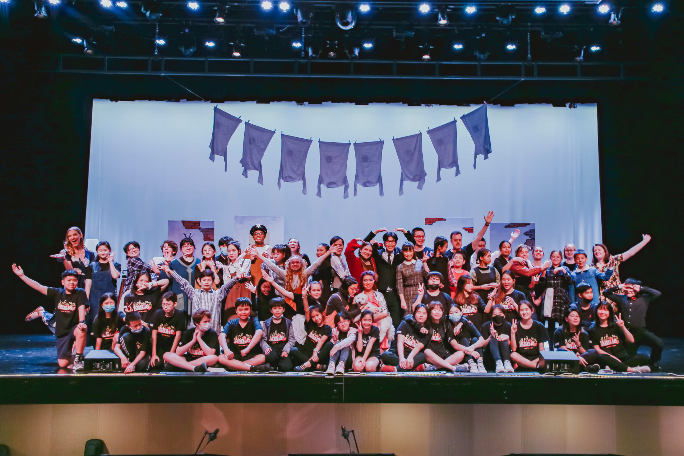 group photo of all the cast and crew of annie jr on the stage