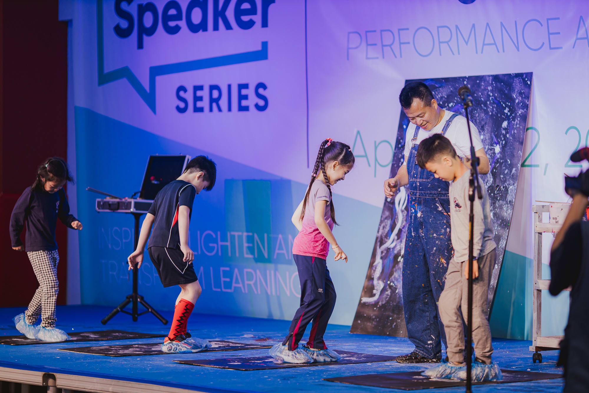students onstage with artist doing painting by stepping on boards