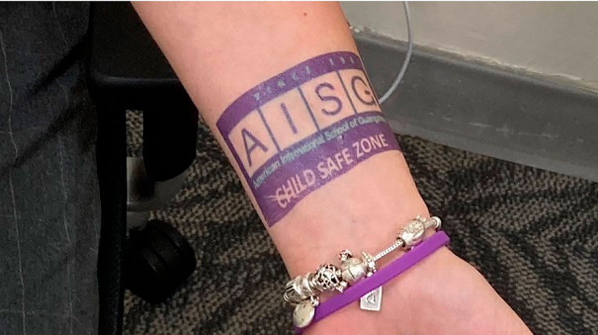 an arm with a tattoo on it that says AISG Child Safe Zone