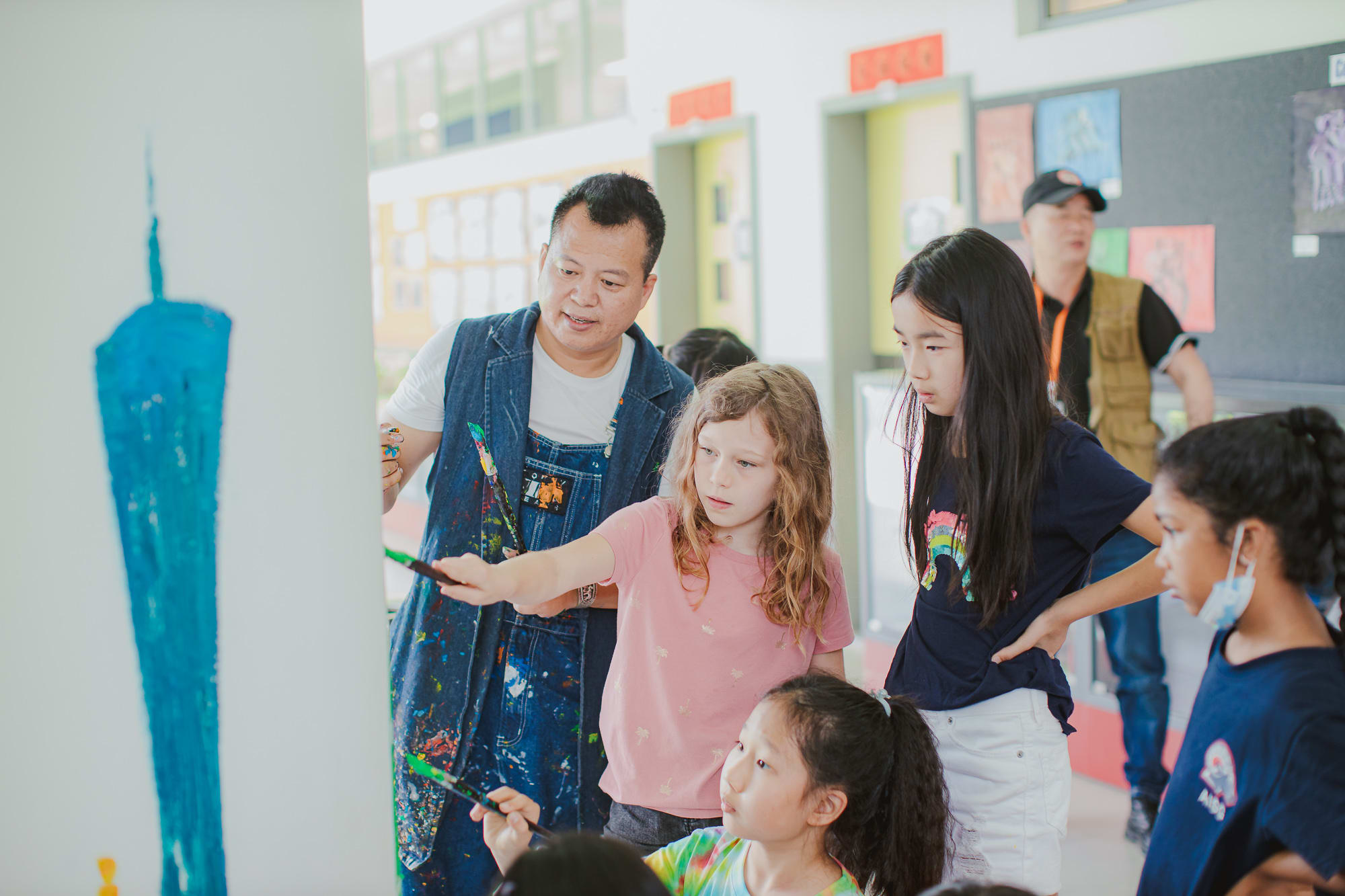 students paint on pillar with artist