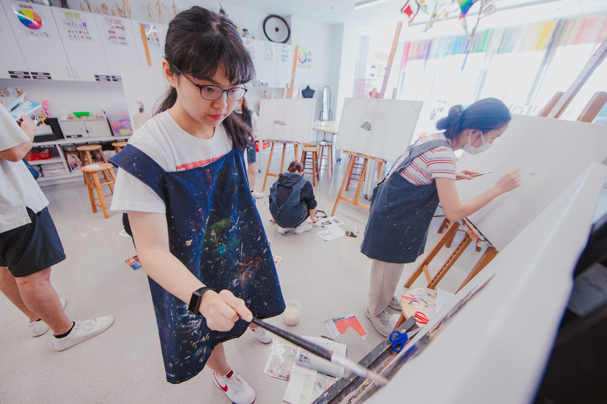 student pasting paper on canvas