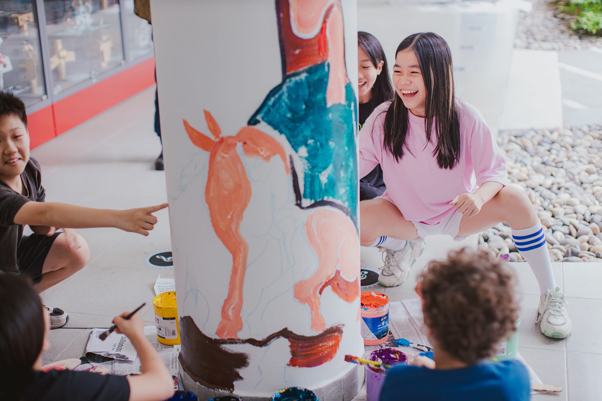 students laugh as they paint on pillar