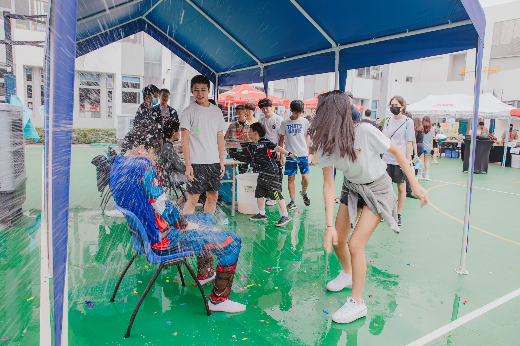 girl throwing a water balloon exploding everywhere at a boy