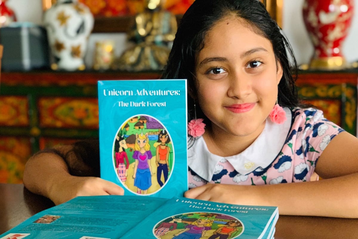 A girl is holding her book and smiling at us