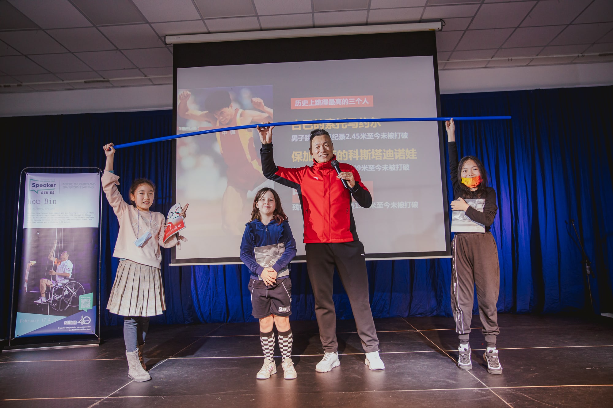 AISG Speaker Series with Hou Bin with elementary volunteers on stage