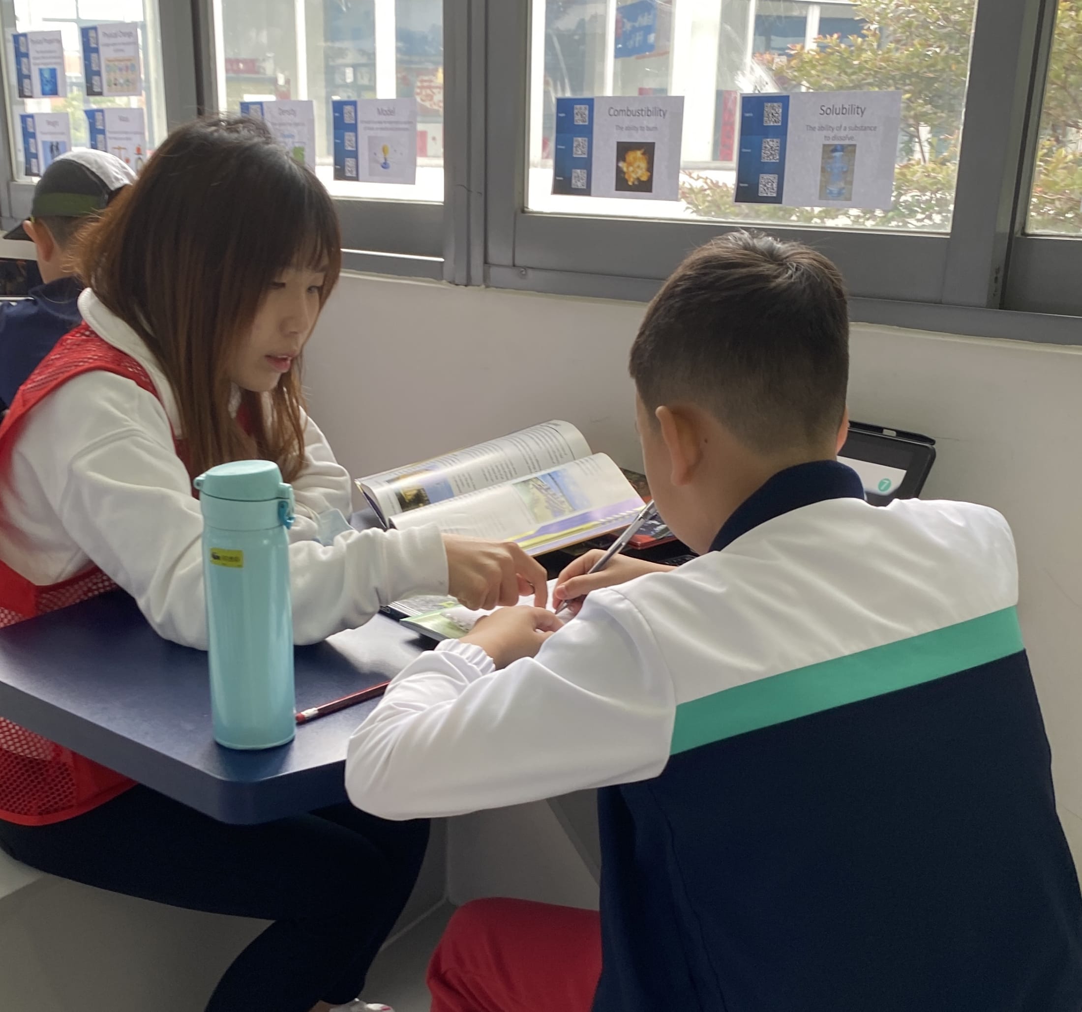 AISG PYPx with a parent volunteer talking with a student about his project