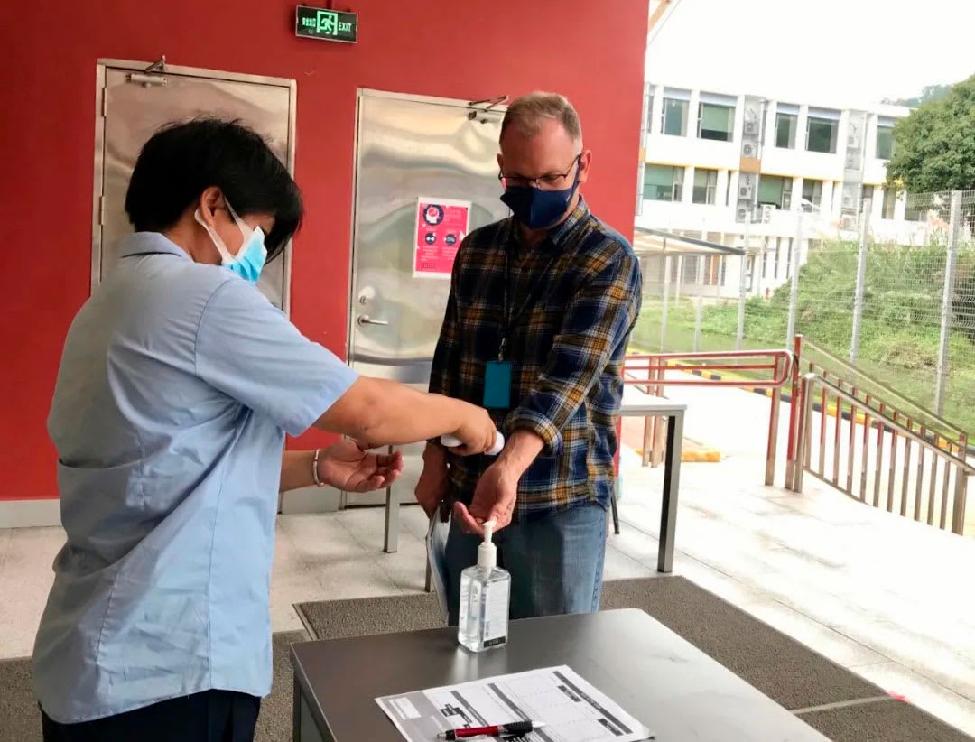 picture of a staff person getting their temperature taken before entering school