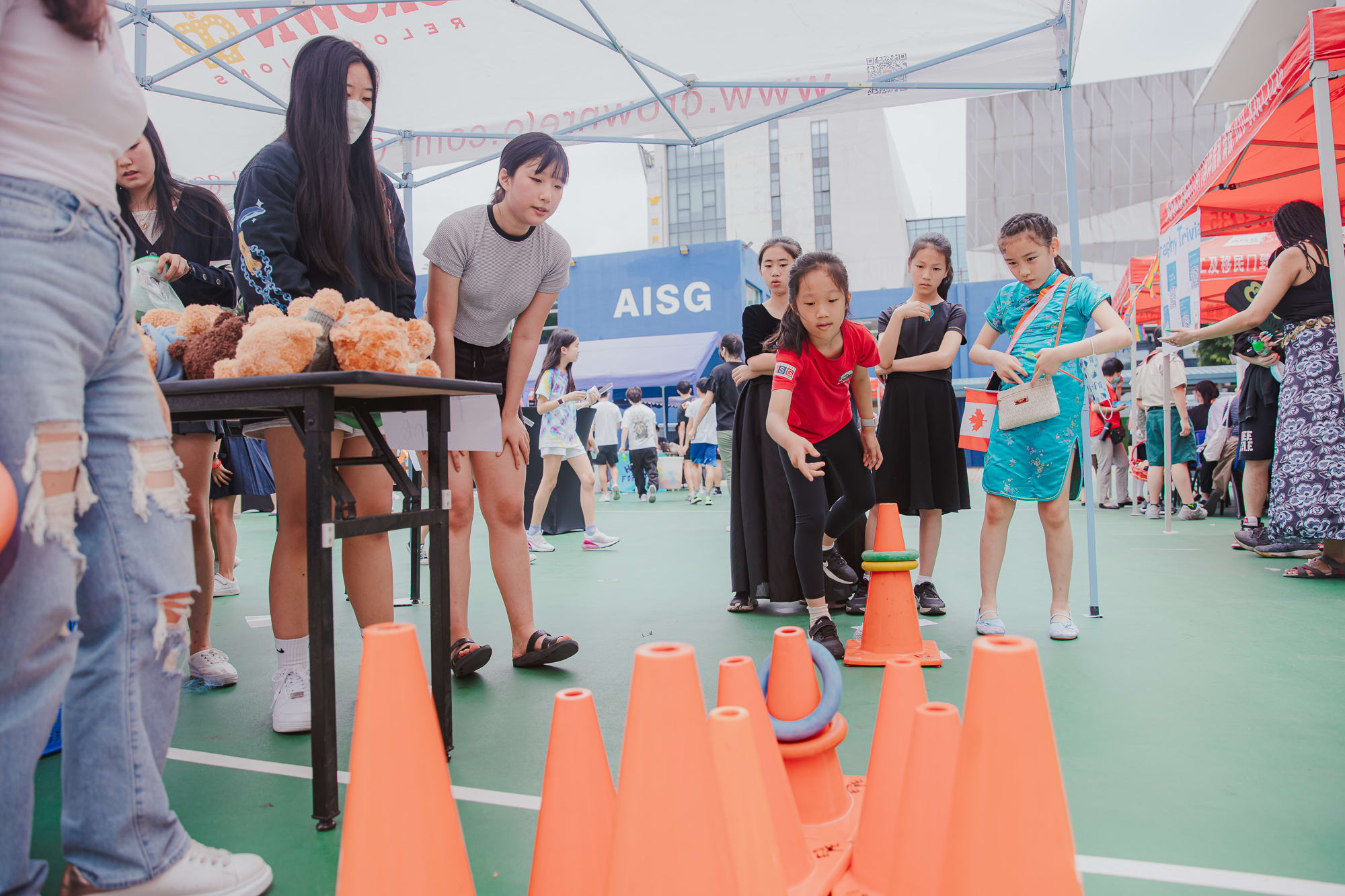 crowd of people watching a girl throw a ring toss at a cone