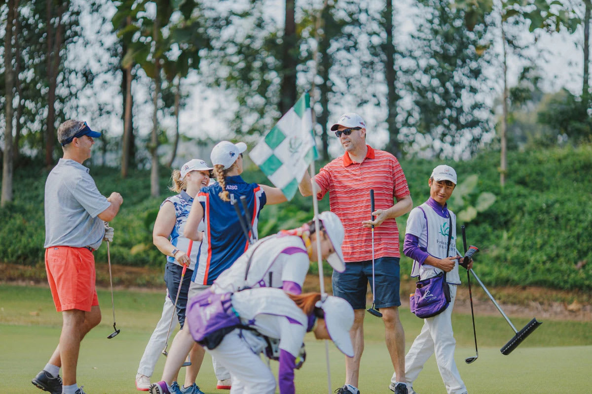 two golfers congratulate each other after one sinks a putt