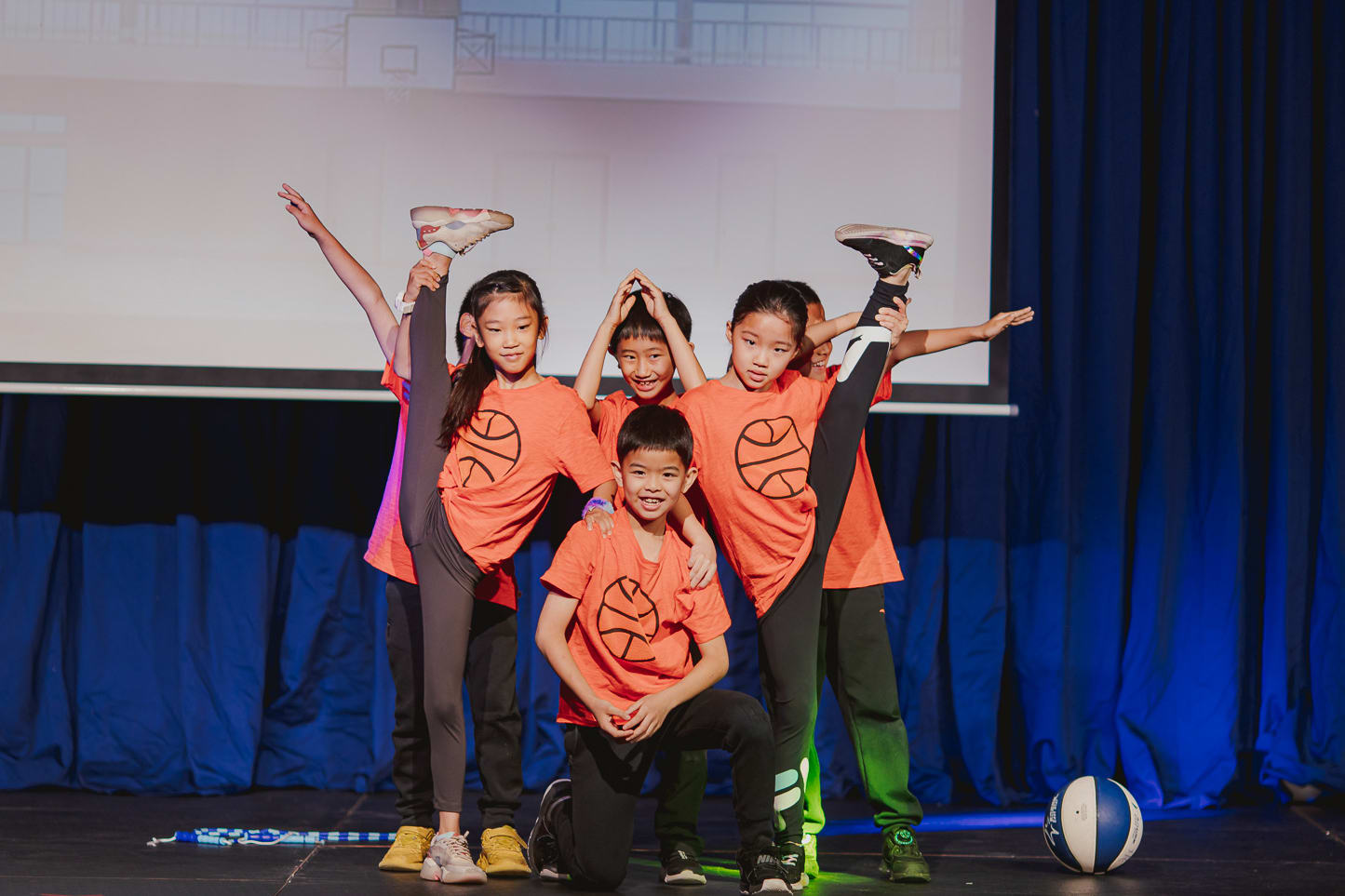 children in orange shirts onstage posing